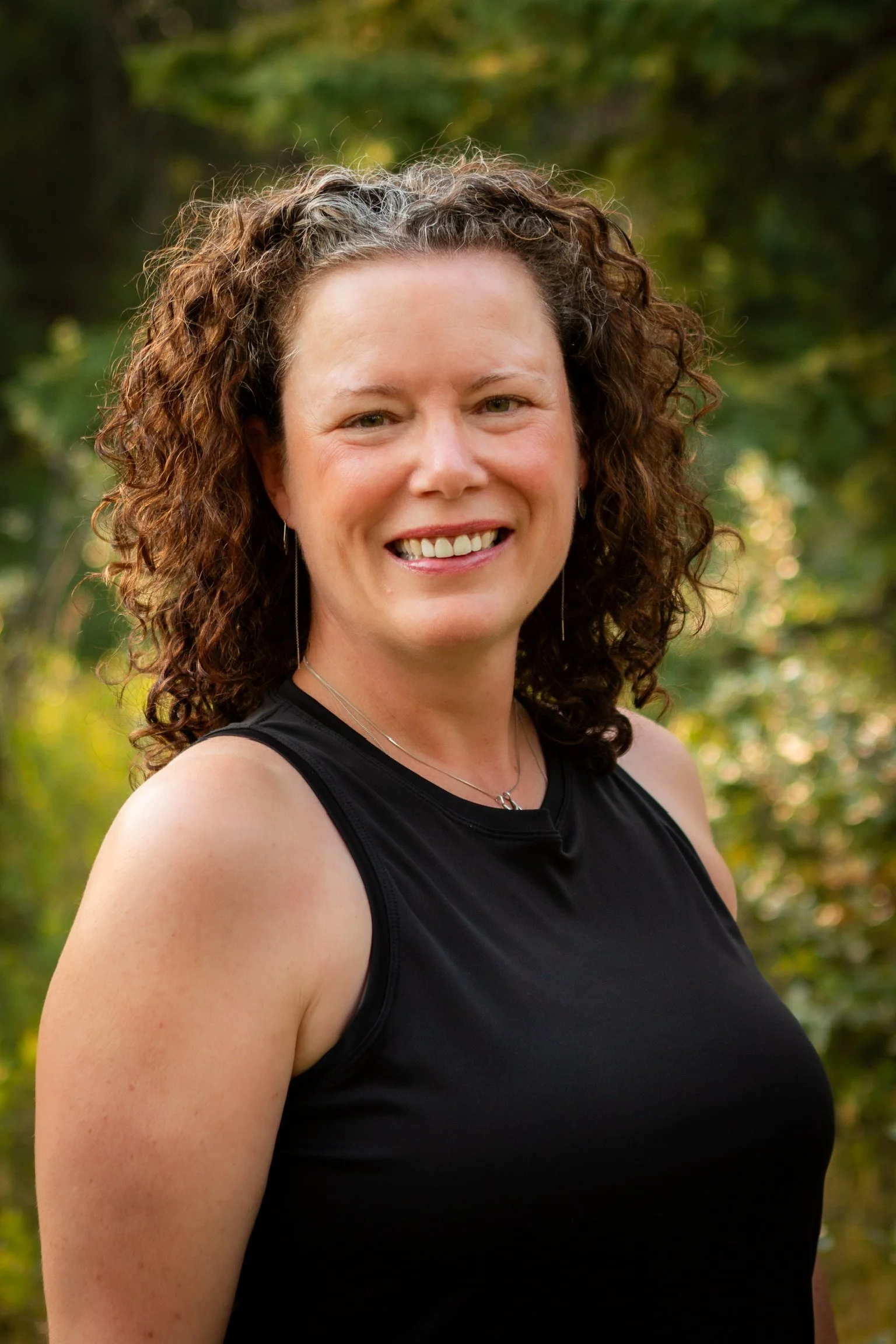 female smiling with curly hair standing outside