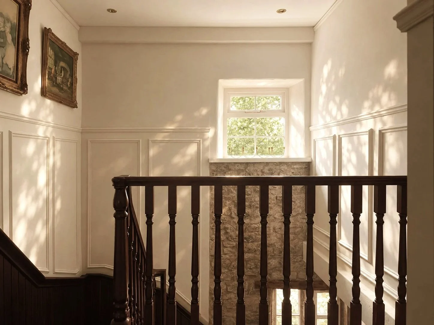 Sunlit traditional staircase landing with dark wooden banister, paneled walls, stone fireplace, window, and framed artwork