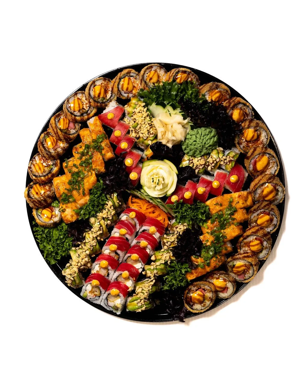 Plate of assorted sushi rolls with various toppings and garnishes in a circular arrangement