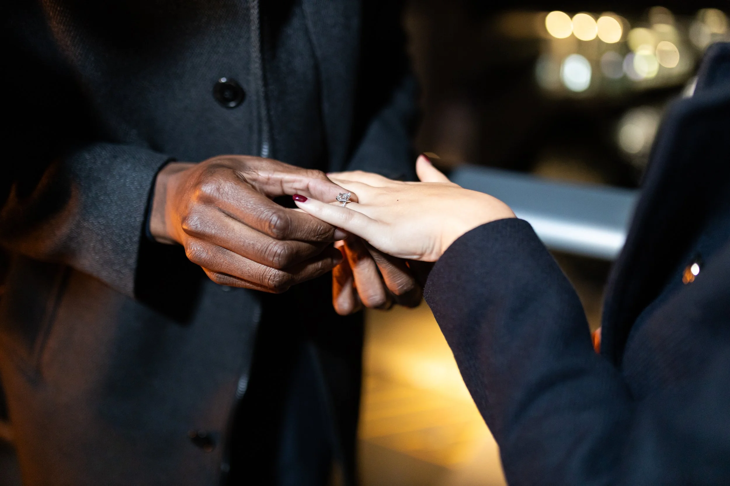 Person placing a ring on another person's finger during a proposal