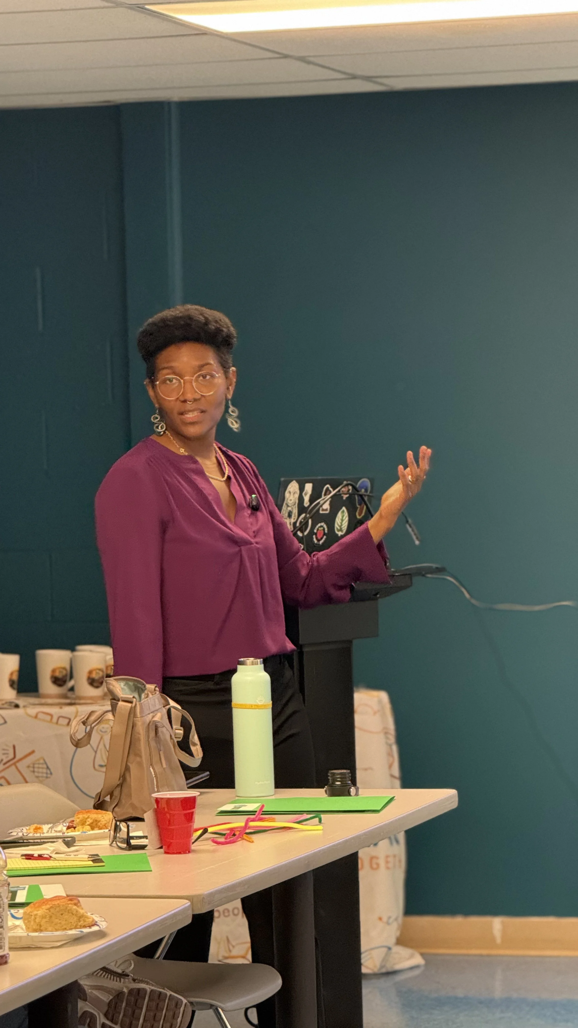 Kenyatta in a purple shirt, talking to people with a computer behind her.
