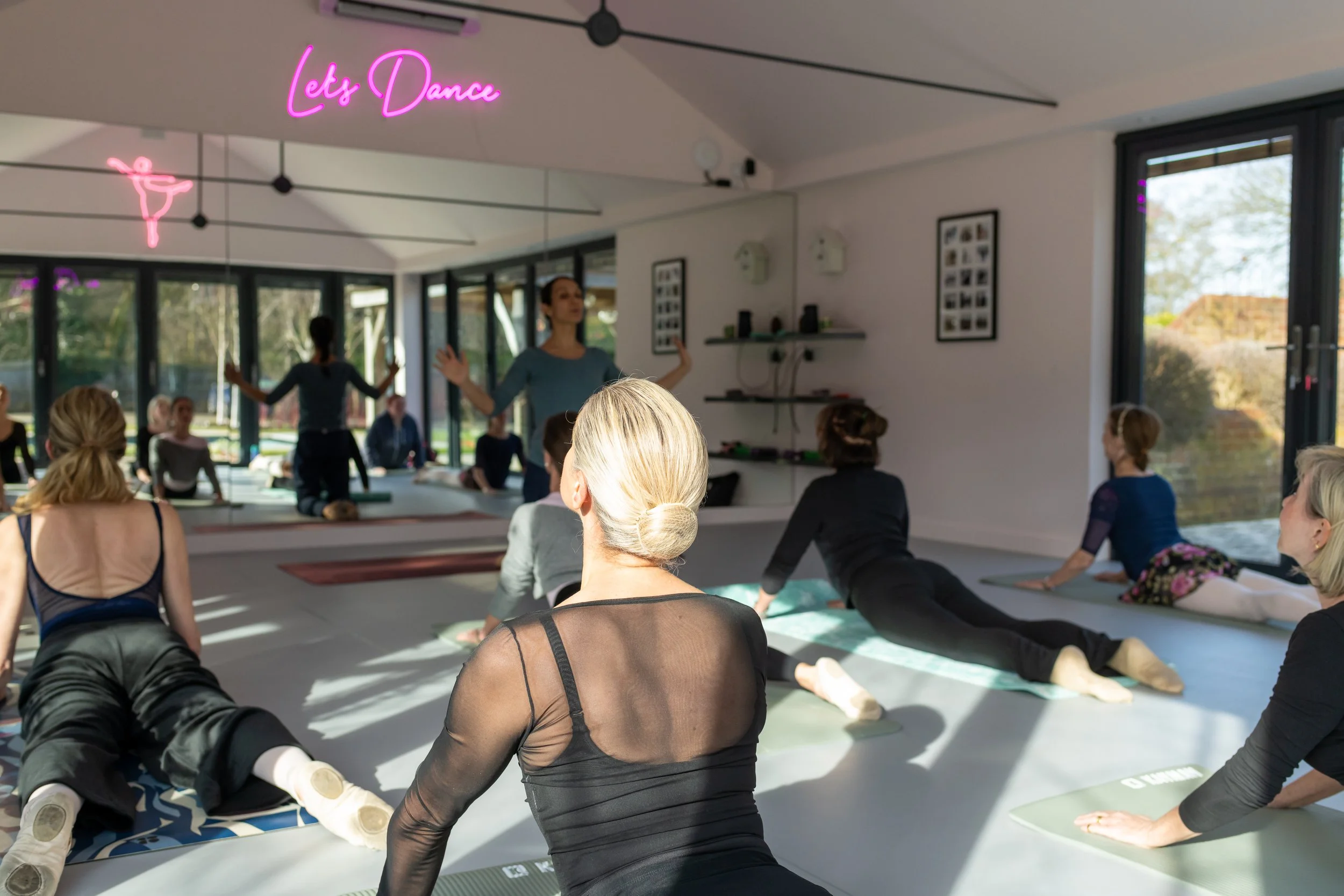 Ballet class with adult dancers stretching in a Pilates class.