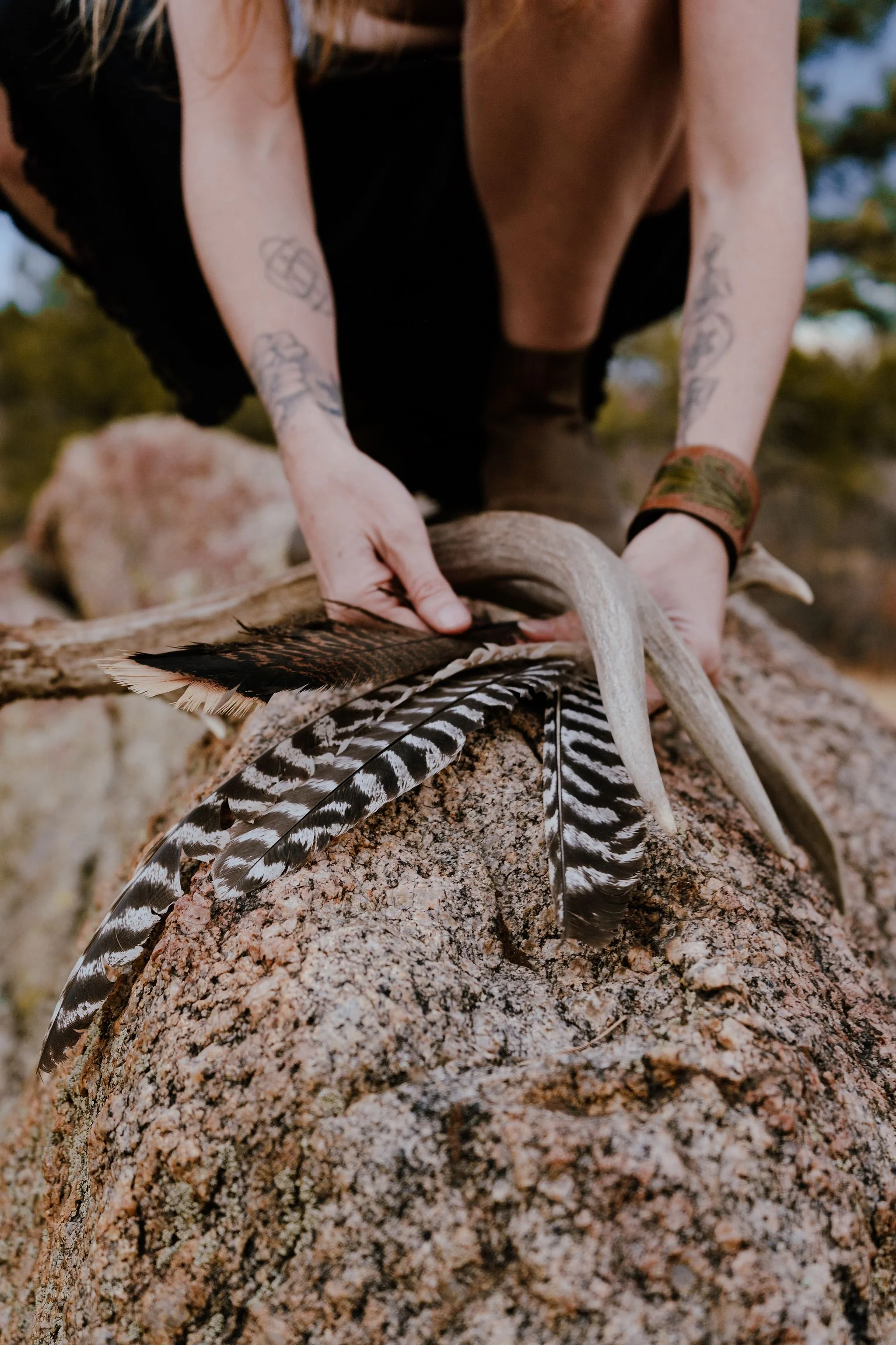 Hands holding antlers and feathers.