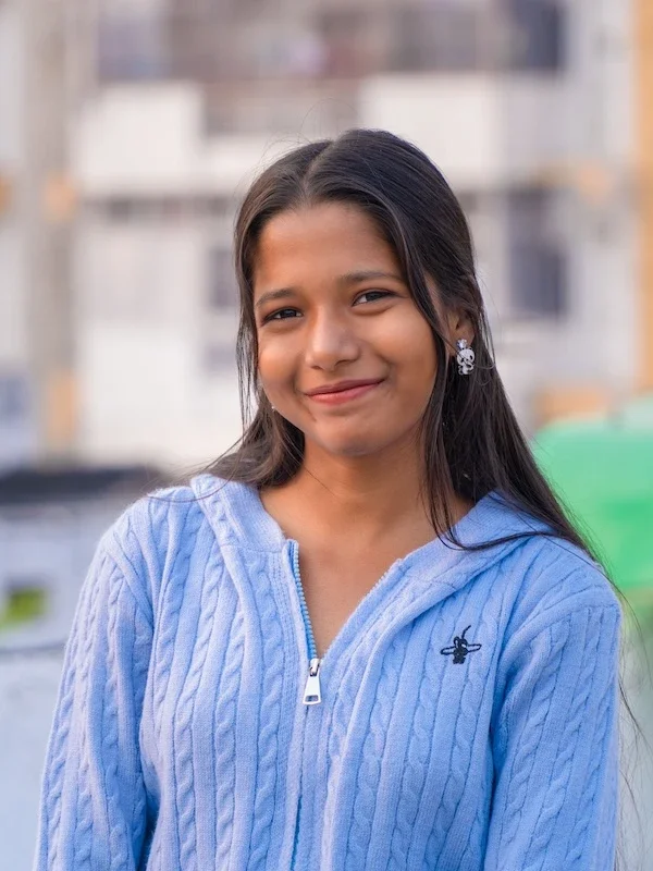 Teen girl smiling in a light blue sweater.
