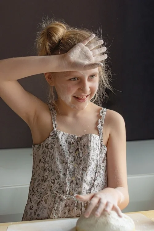 A girl baking and smiling.