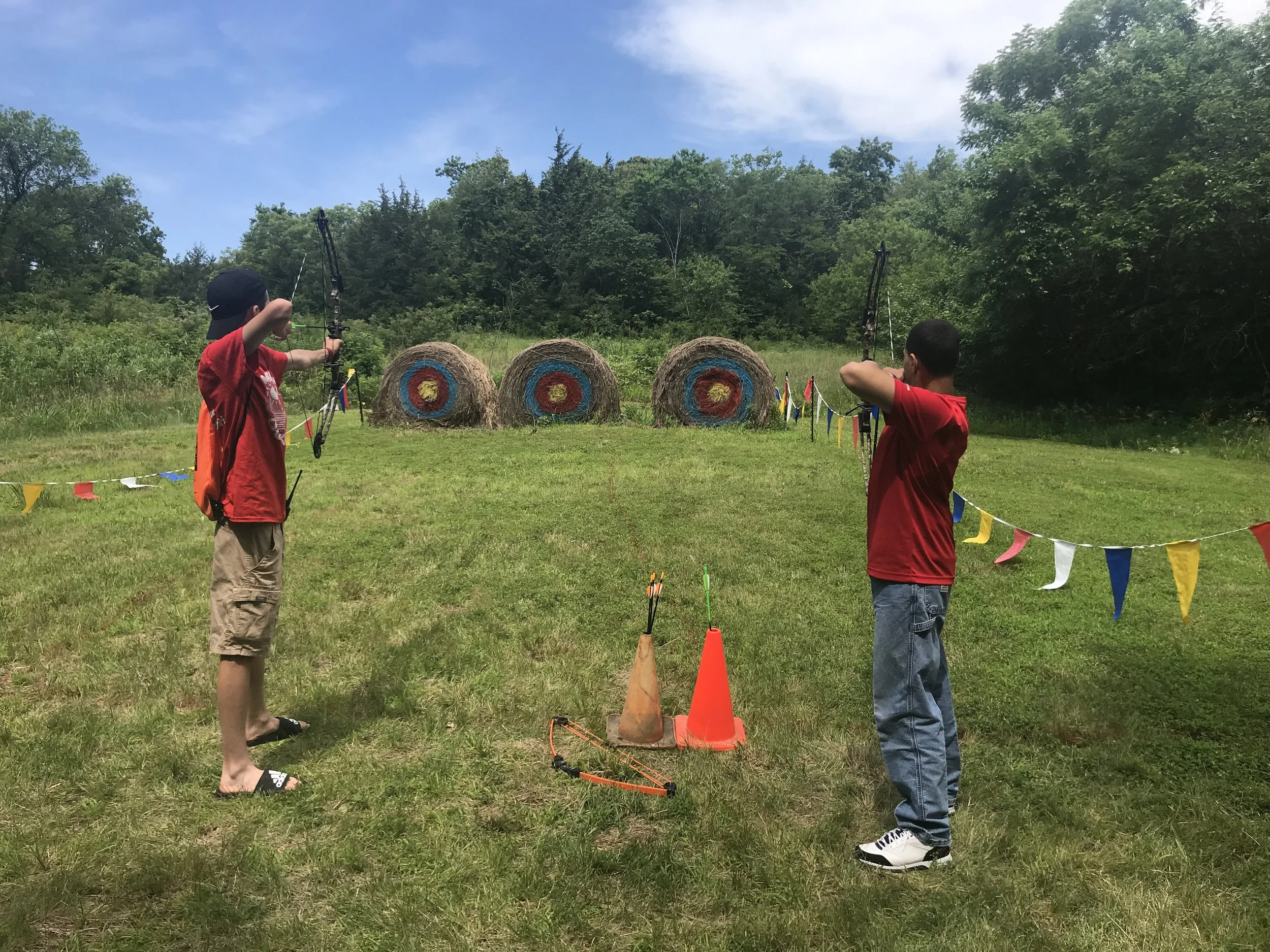 Two people practicing archery in an outdoor area with targets.