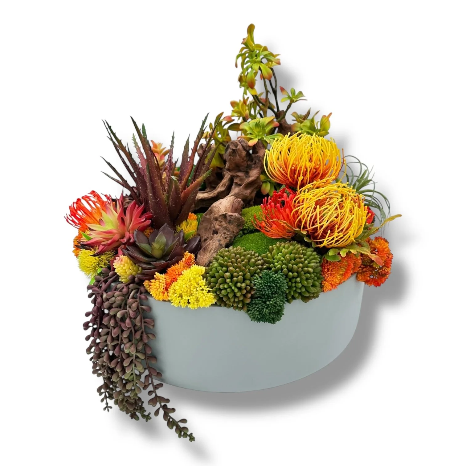 Arrangement of colorful succulents and desert plants in a white vase, including yellow, orange, purple, and green varieties with some wooden decorative pieces.