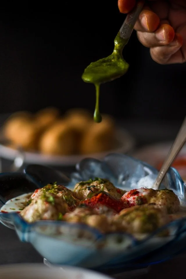 Close up of Dahi wada and a spoonful of green chutney
