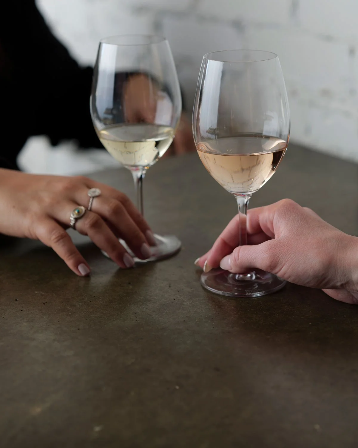 Two hands hold a glass of white wine and a glass of rose wine