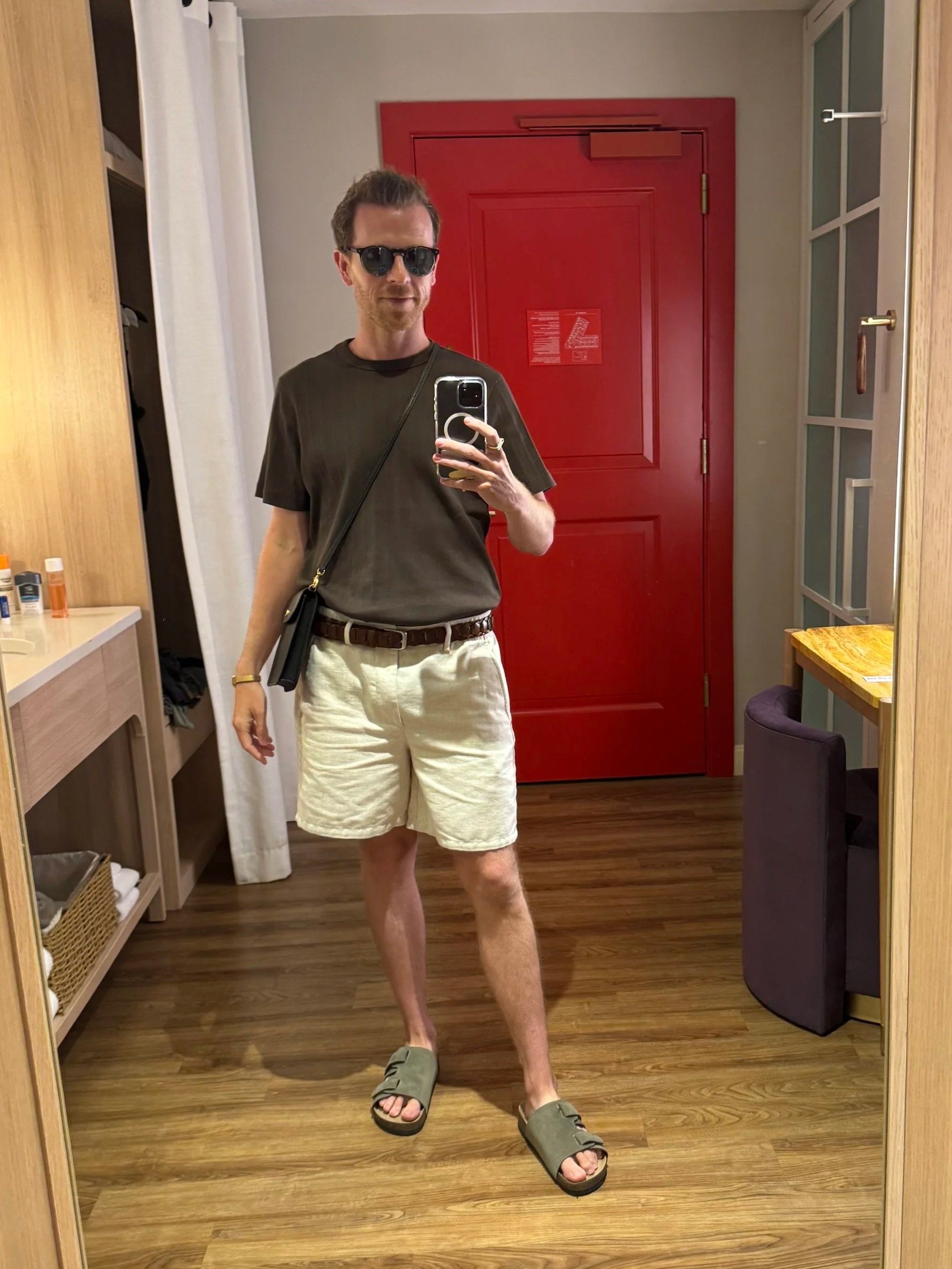 The final outfit stayed close to the original plan: a tucked dark tee, light linen shorts, woven belt, green sandals, sunglasses, and a crossbody bag for an easy, polished, walkable look.