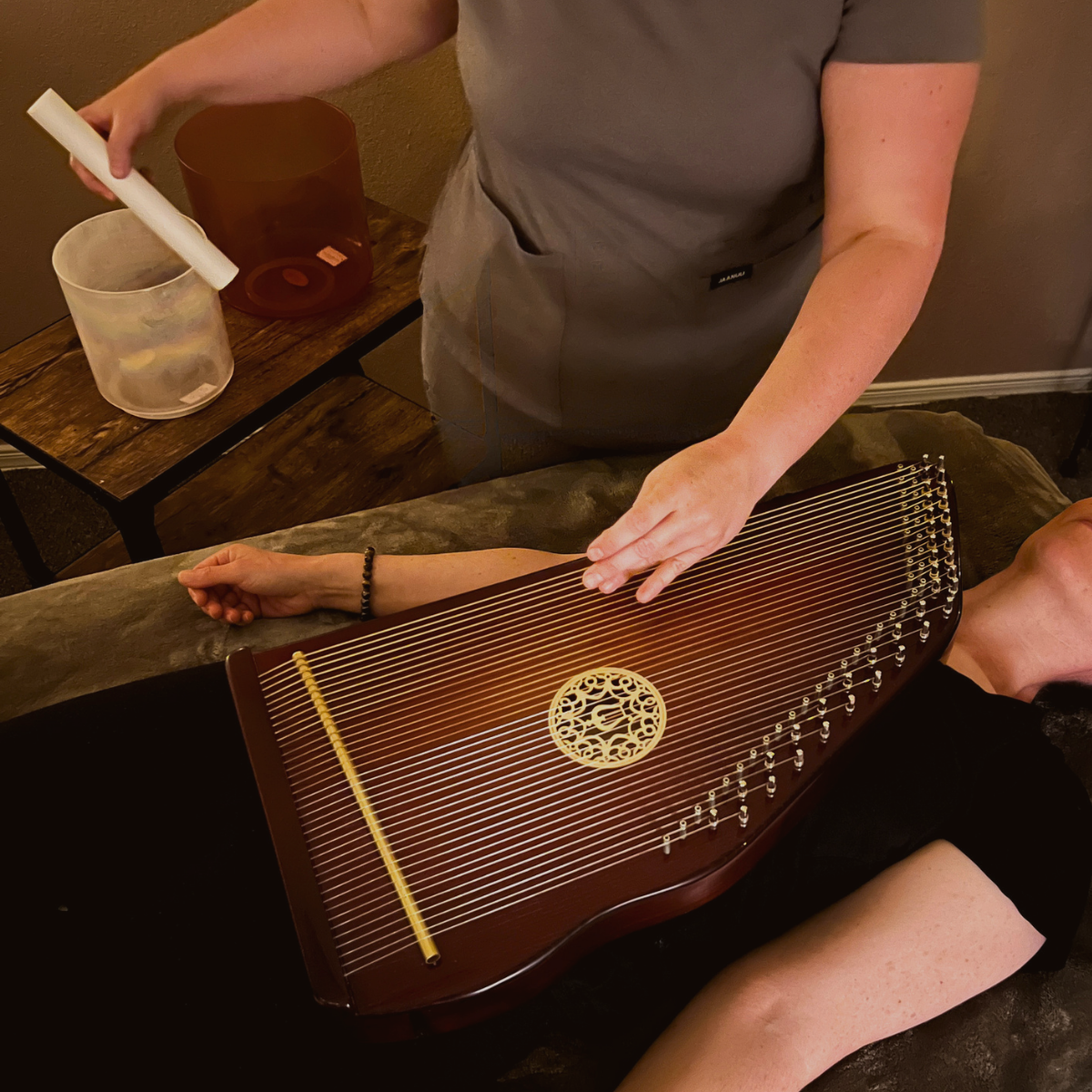 Client receiving a sound immersion session with a therapy harp played on the body.