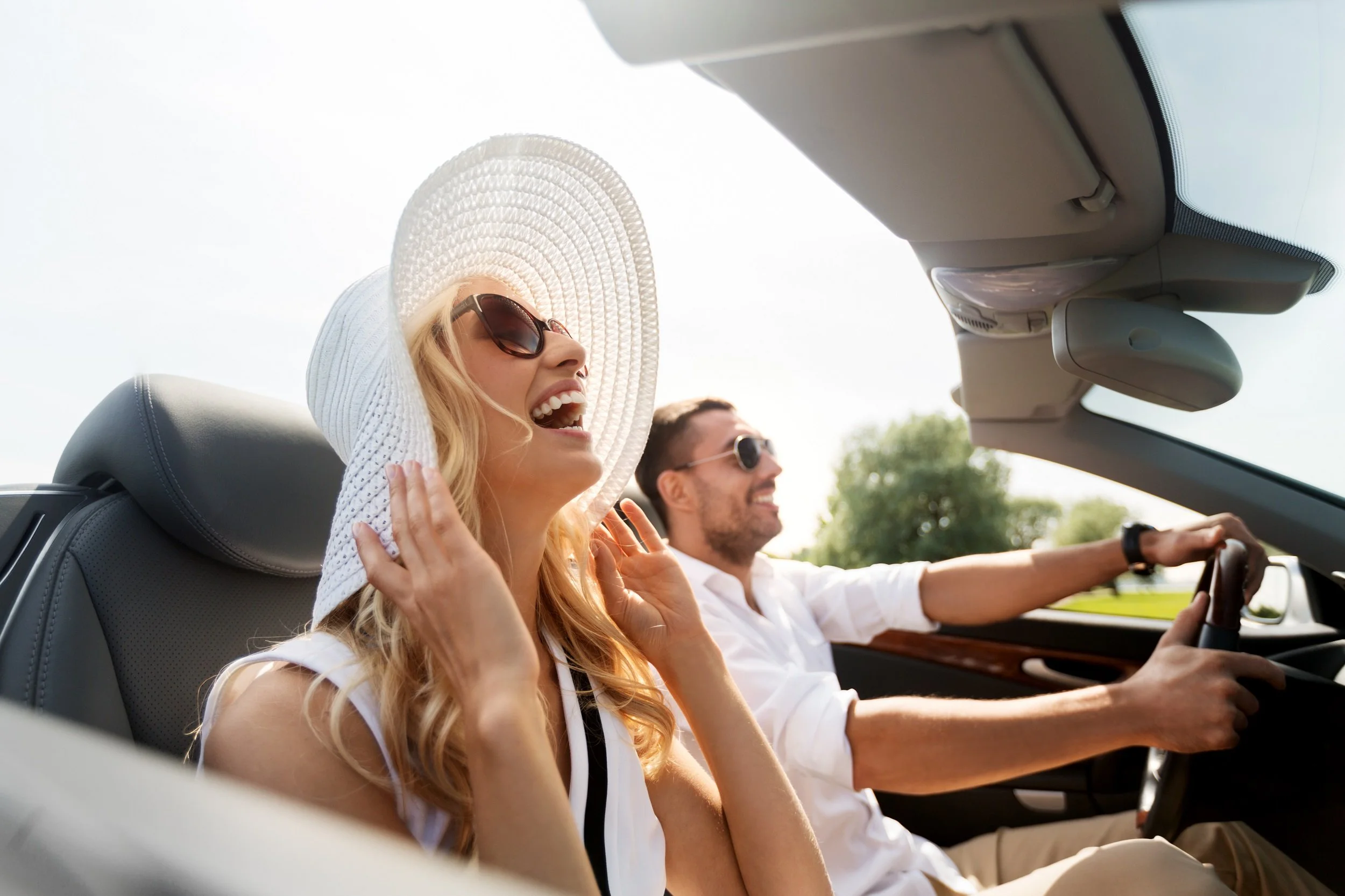 happy man and woman driving in convertible car outdoors