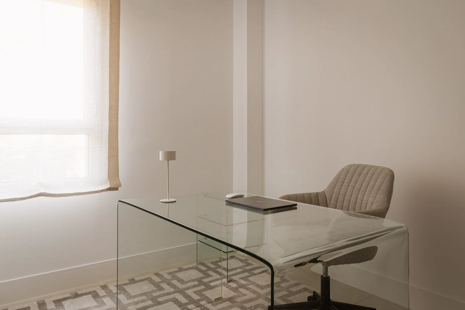 Minimalist home office interior featuring a transparent glass desk.