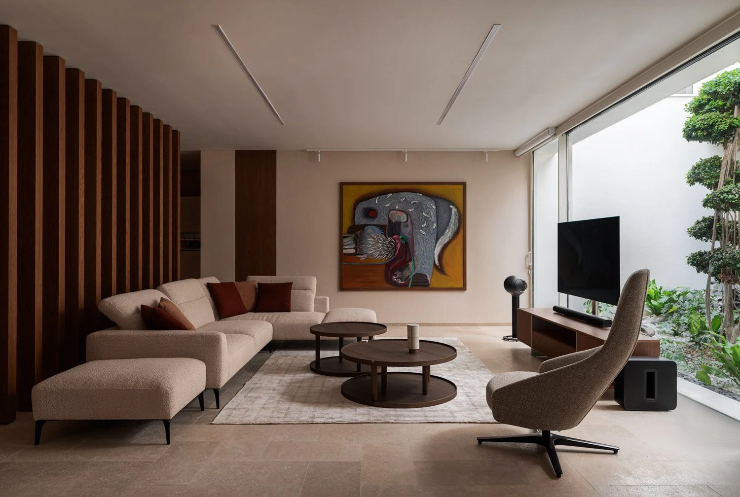 Modern living room with beige sectional sofa, brown cushions, round coffee tables, abstract wall art, flat-screen TV on wooden stand, textured armchair, large window with greenery outside.