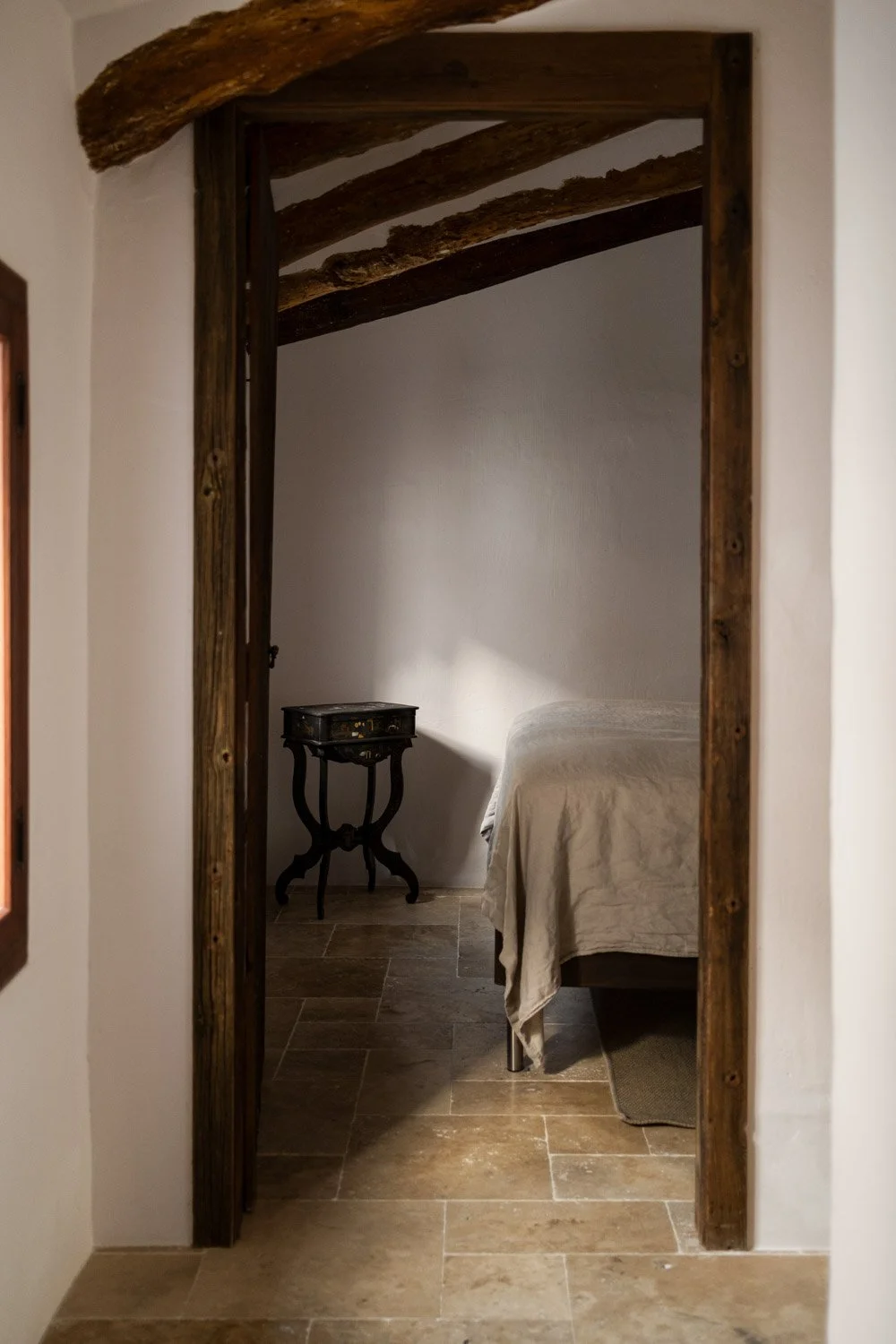 View into bedroom through restored wooden door frame with original ceiling beams in Altea residence