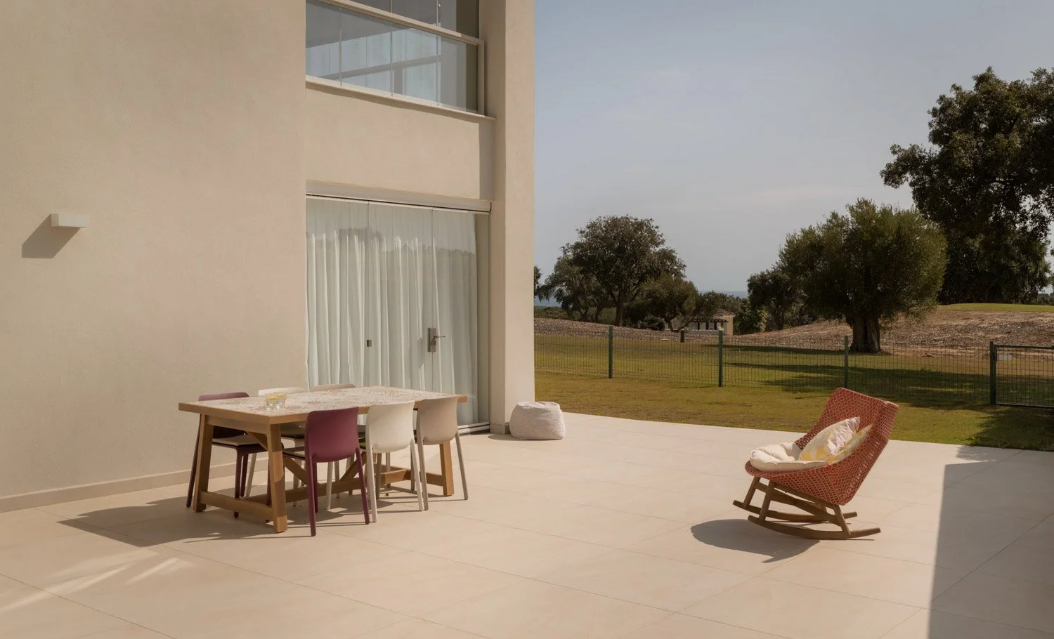 Minimalist outdoor dining area and rocking chair on a sunlit Sotogrande terrace.