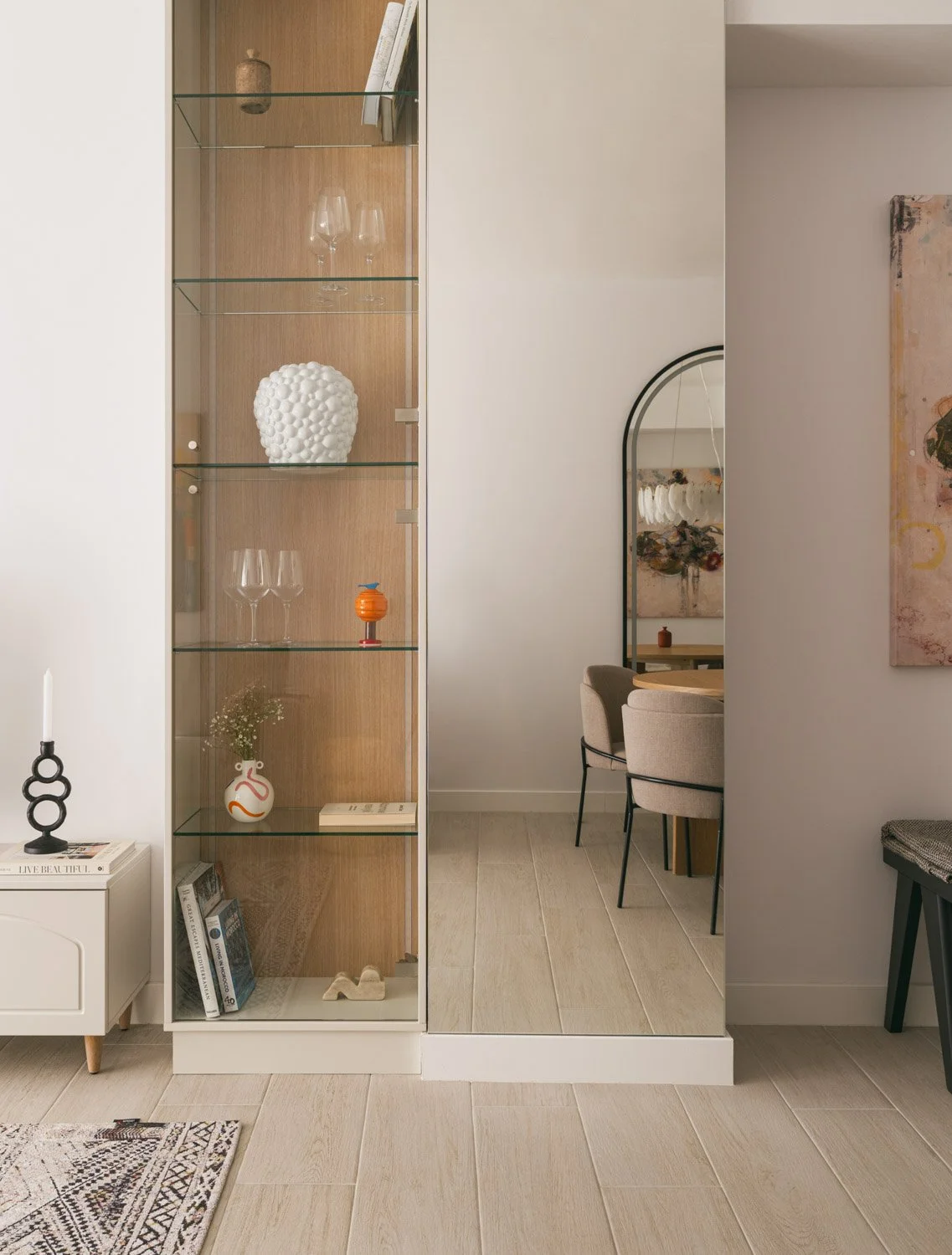 Modern glass display cabinet with wood paneling and decorative styling items.