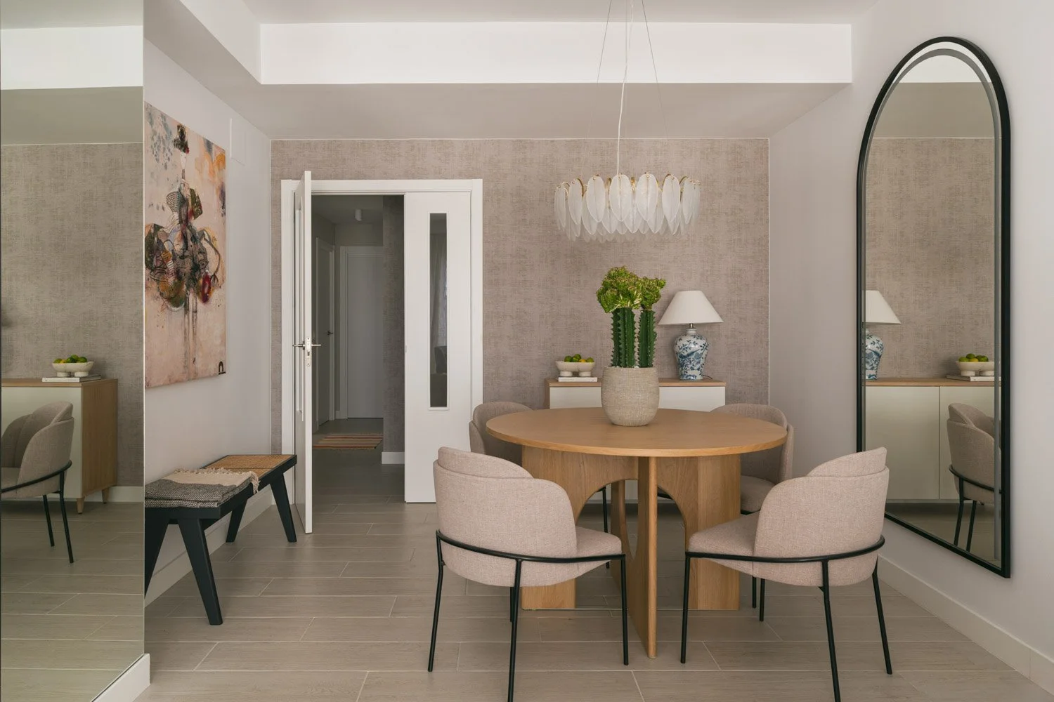 Modern dining area with a round oak table and unique feather chandelier.