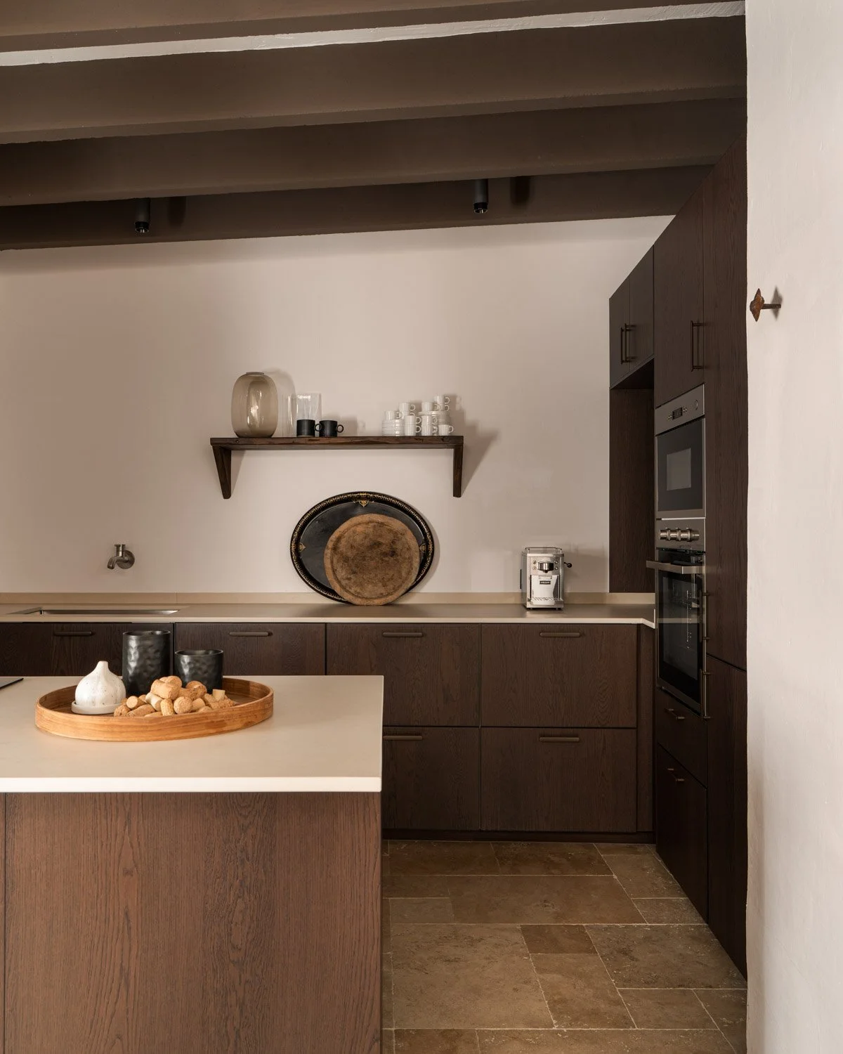 Dark oak kitchen with stone floors and antique decorative trays in Altea historic residence