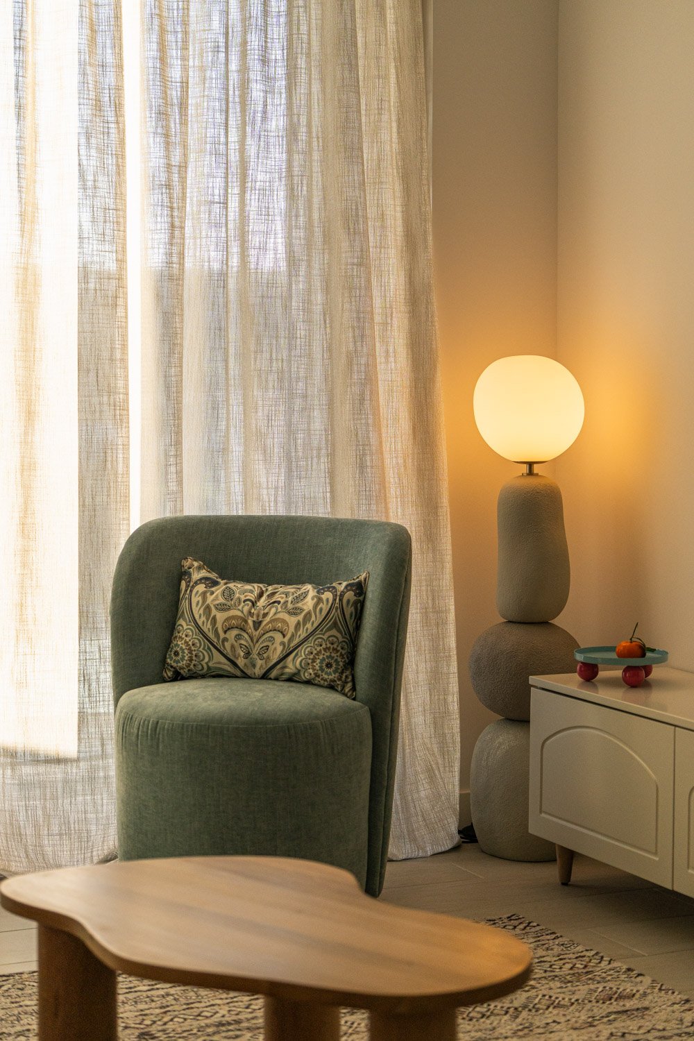 Living room corner with a green curved armchair and organic stone lamp