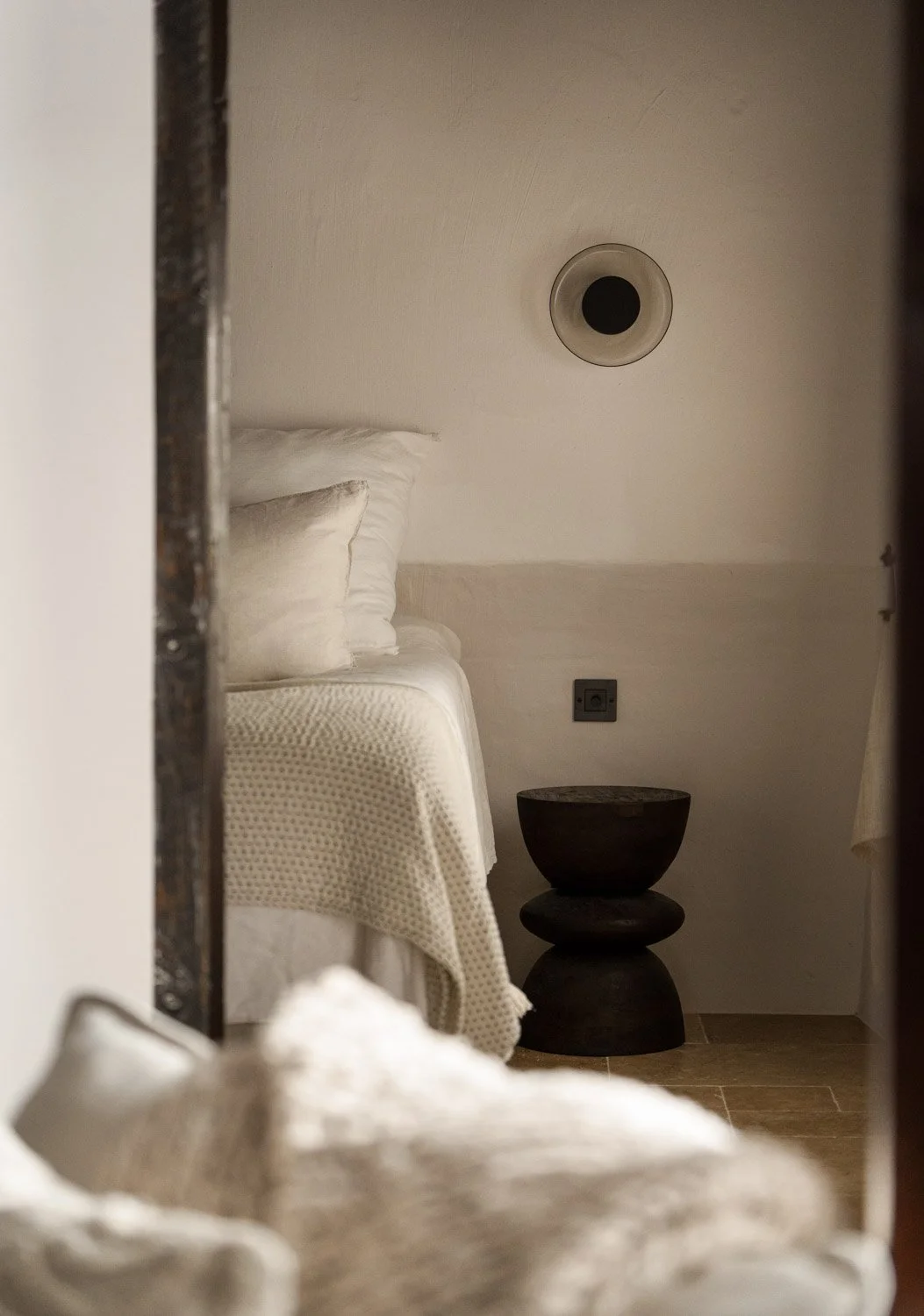 Bedroom doorway view with linen bedding and dark turned wood side table in Altea residence
