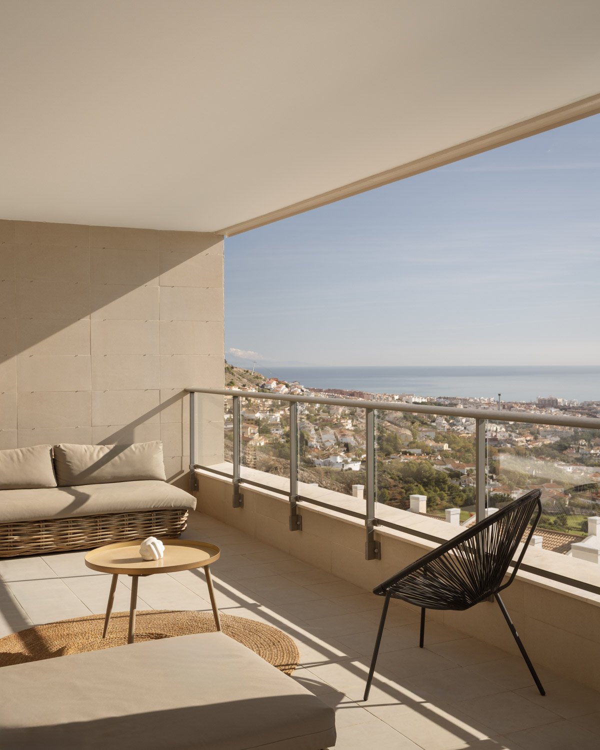 Sunny outdoor lounge terrace with comfortable seating and panoramic coastal views.