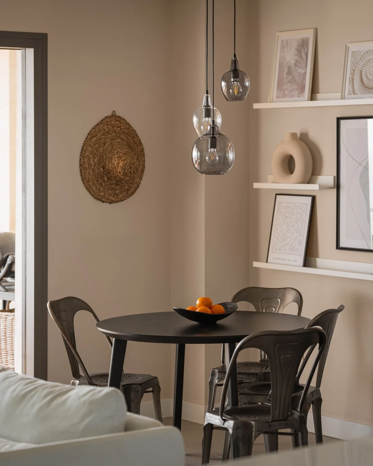 Round black dining table with metal chairs and glass pendant lights.