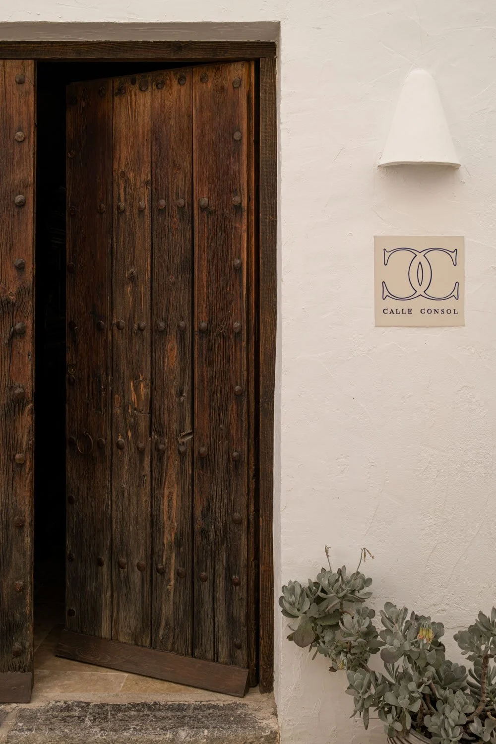 Weathered wooden entrance door with iron studs and Calle Consol logo plate in Altea old town