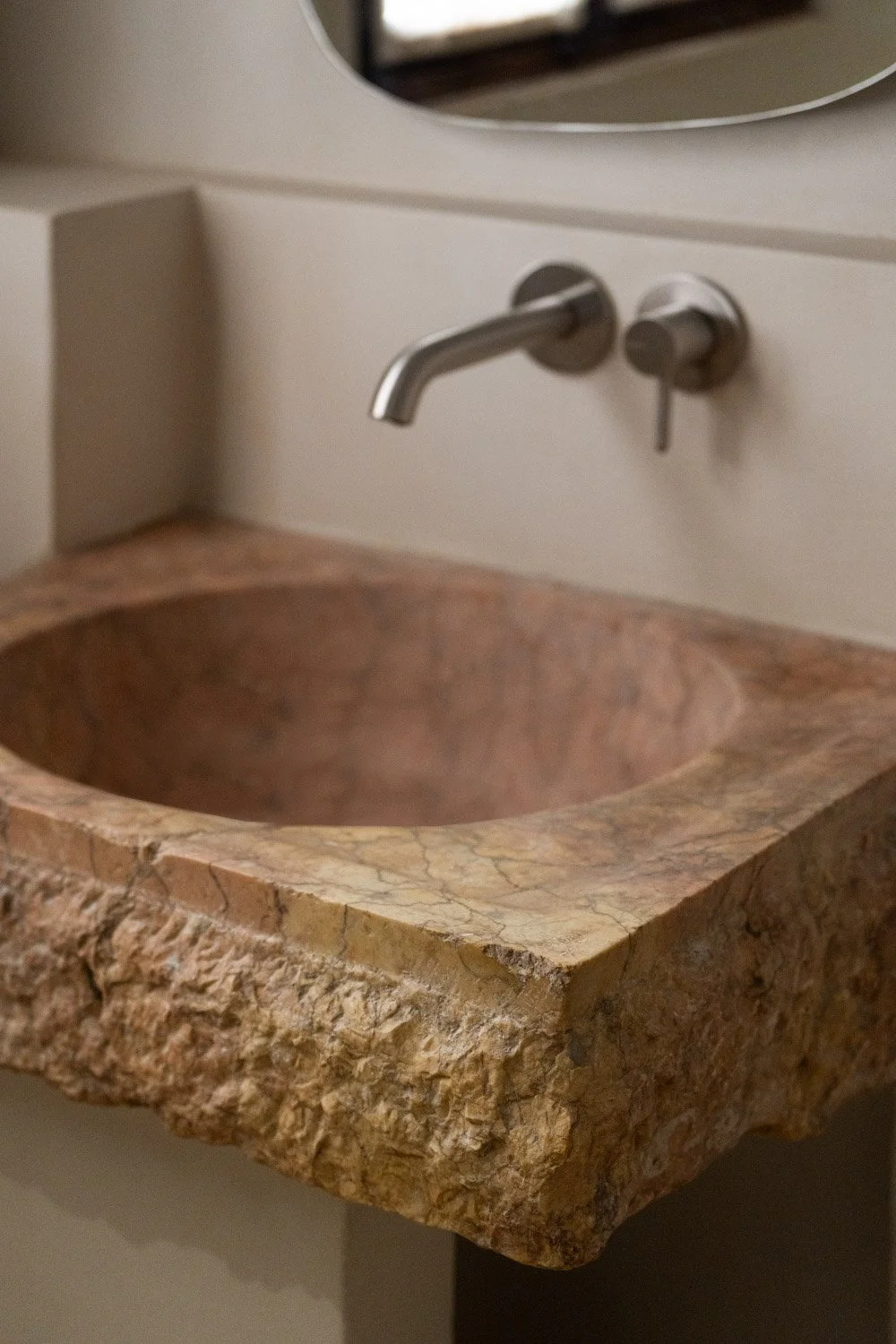 Close up of hand carved stone bathroom basin with raw natural edges in Atelier Valencia project
