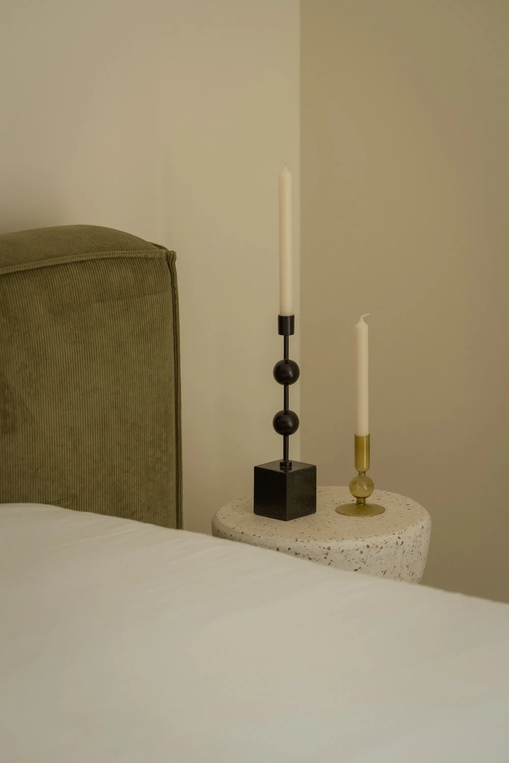 Modern bedroom styling with a terrazzo nightstand and black candle holders.