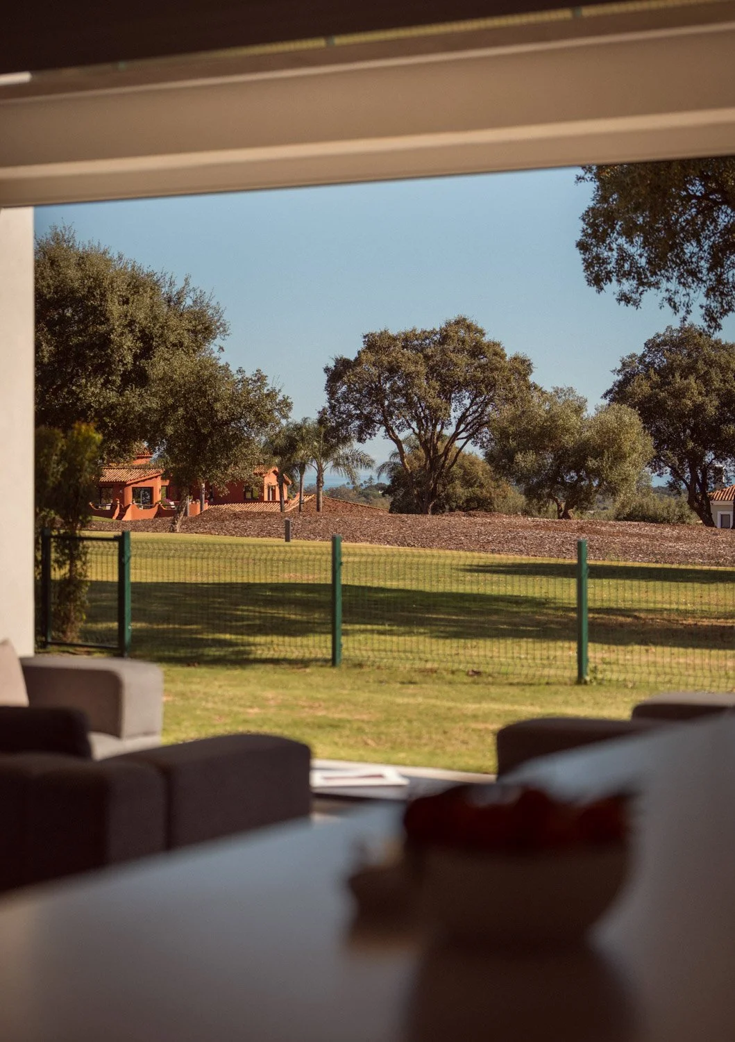 Indoor view looking out to a green garden and distant sea.