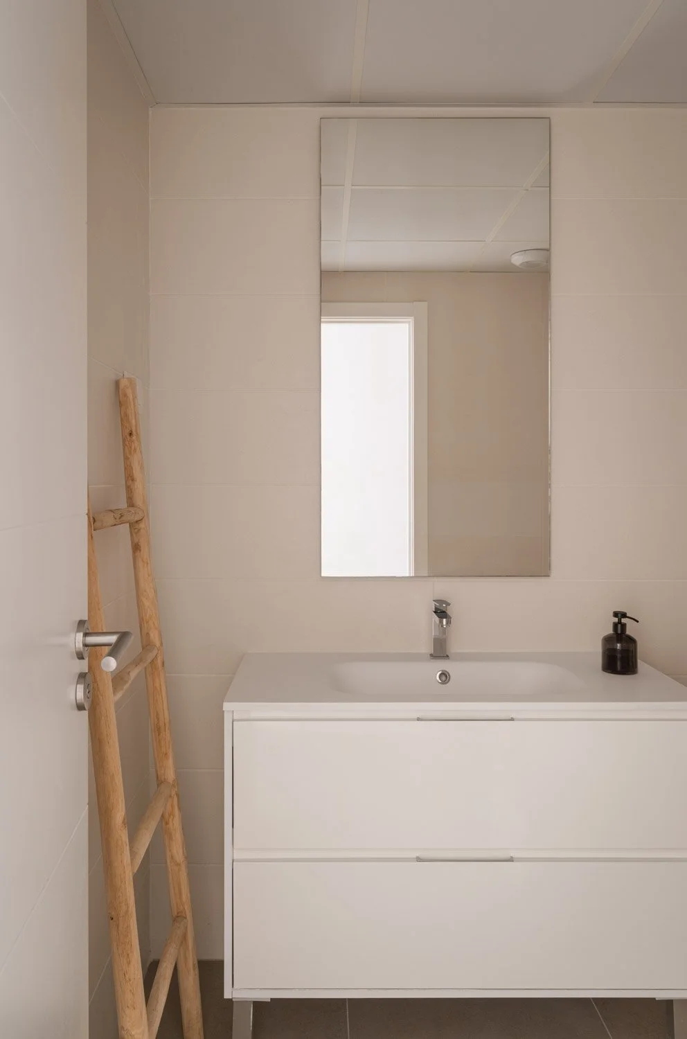 Modern white bathroom vanity with sink, mirror, and decorative wooden ladder