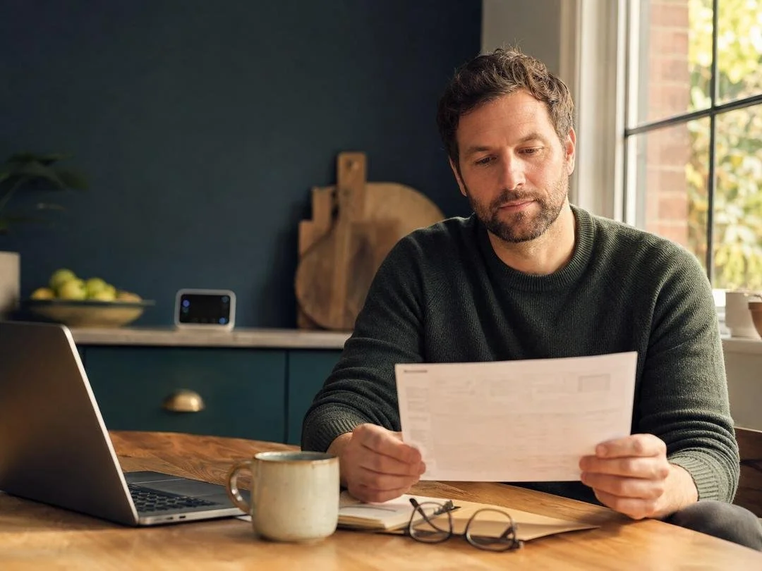 Parent reviewing paperwork for independent educational evaluations at a kitchen table with a coffee mug nearby.