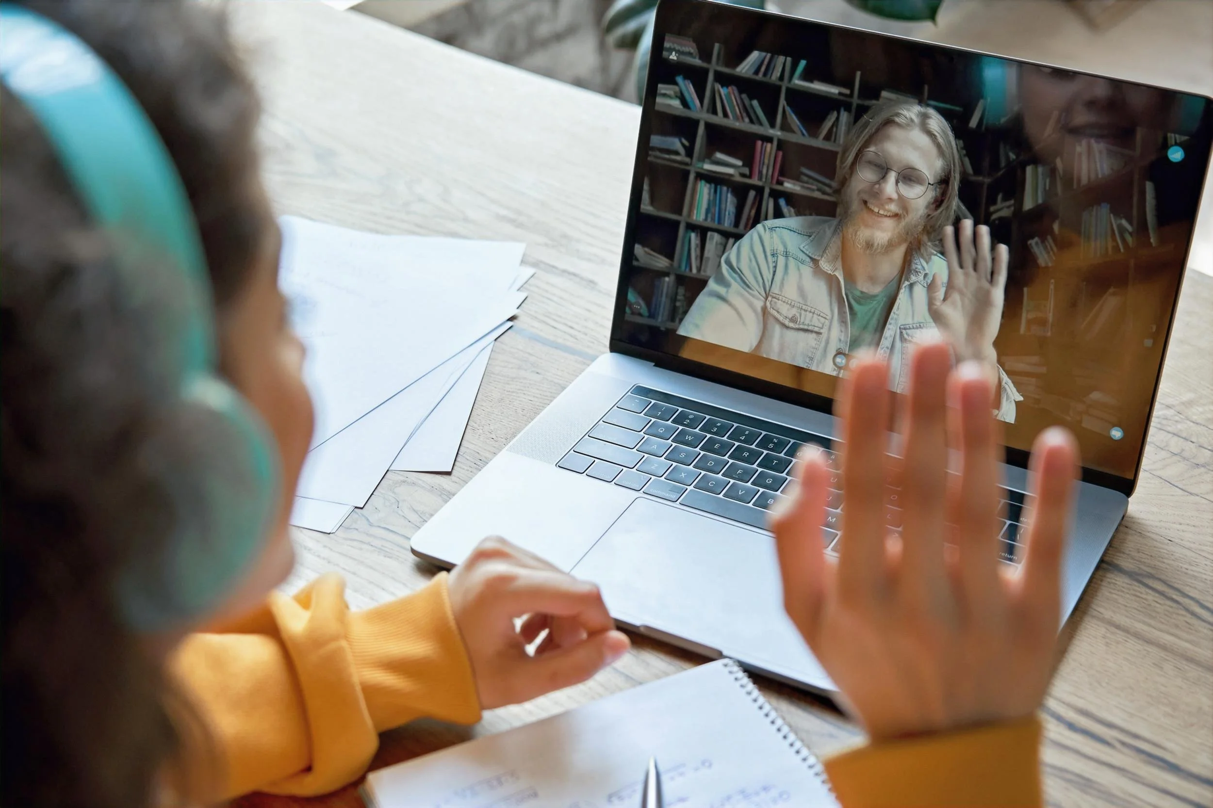 Child participating in a virtual therapy session at home with a clinician on a laptop.