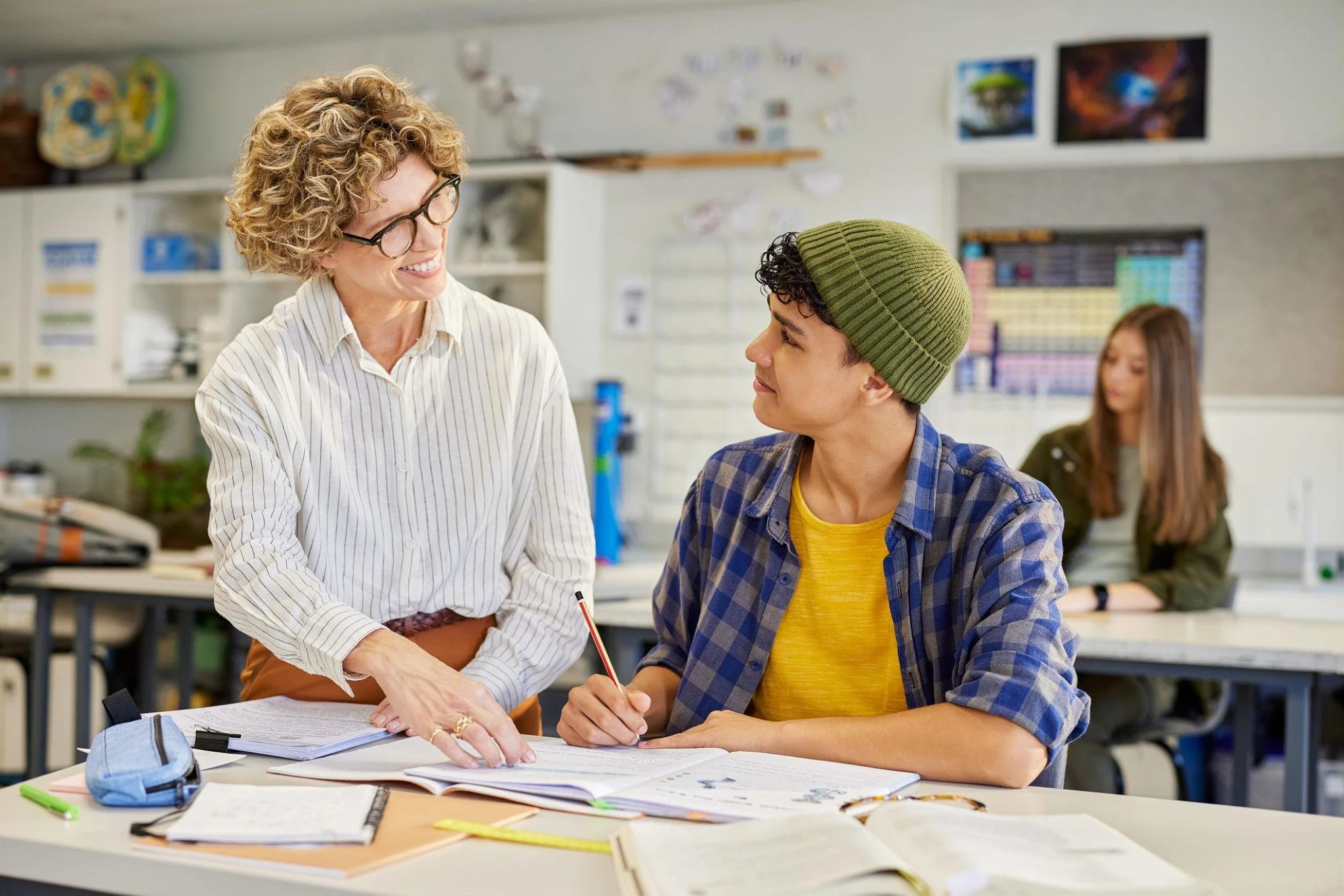 Teacher providing one-on-one support to a teenage student during a classroom lesson