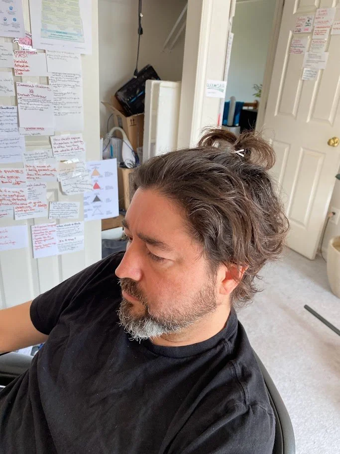 Picture of Tyler Rockwell in his office with lots of cards and notes on the wall, all part of rebuilding my identity.