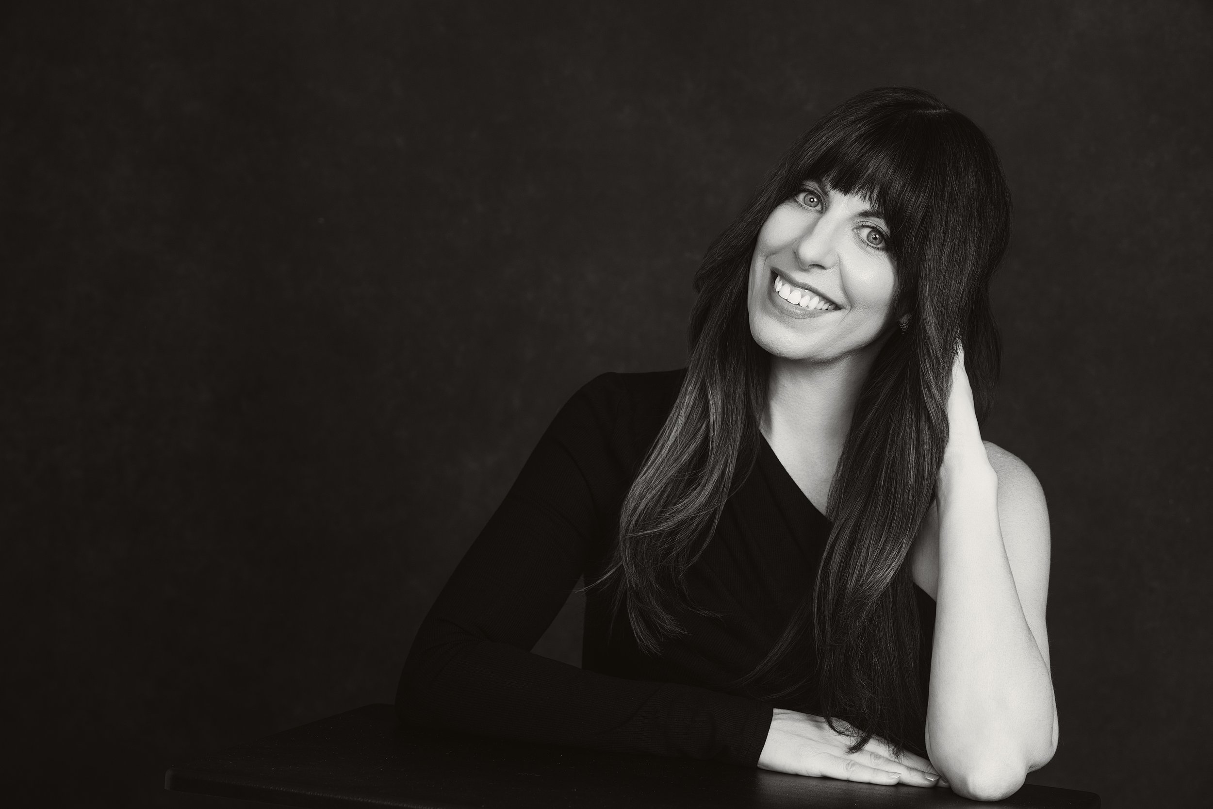 Black-and-white portrait of Dani Audette, founder of Audette Law, smiling with her head tilted and one hand resting in her hair.