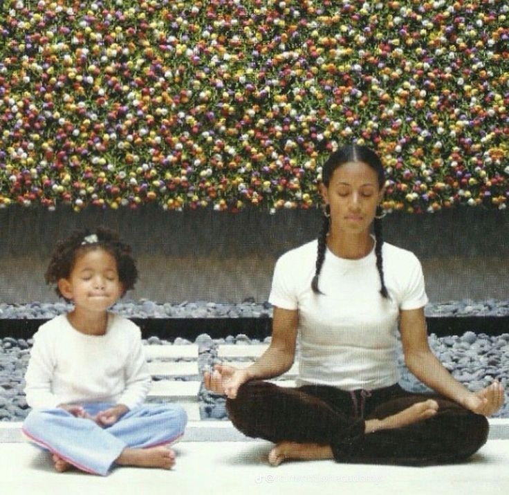 Image of Black woman and her daughter meditating in chic minimalist outfits