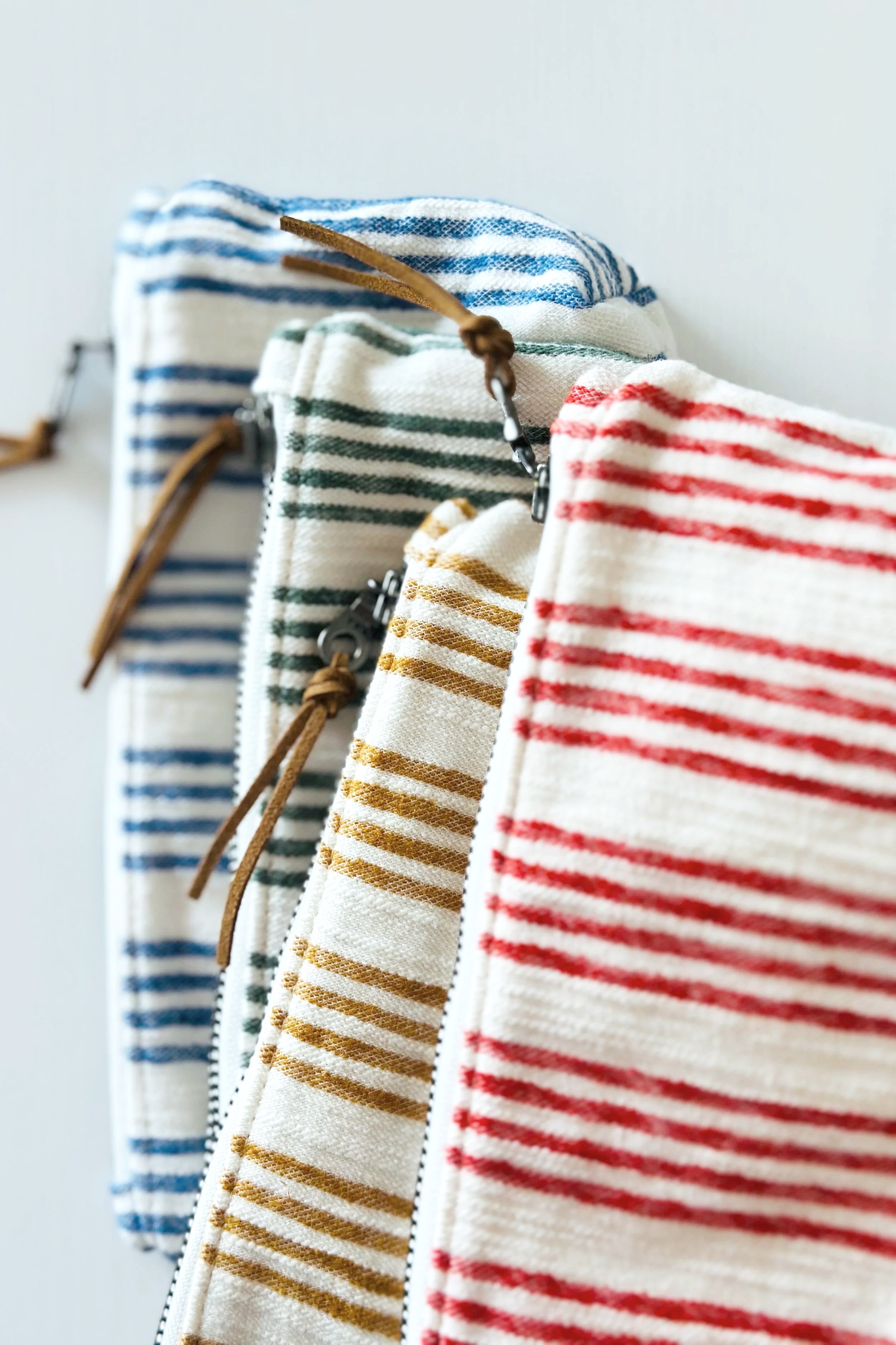  Handmade striped linen zipper pouches in mustard, red, and blue — one-of-a-kind upcycled accessories from The Thrift Edit by Wood and Threads by Jen 