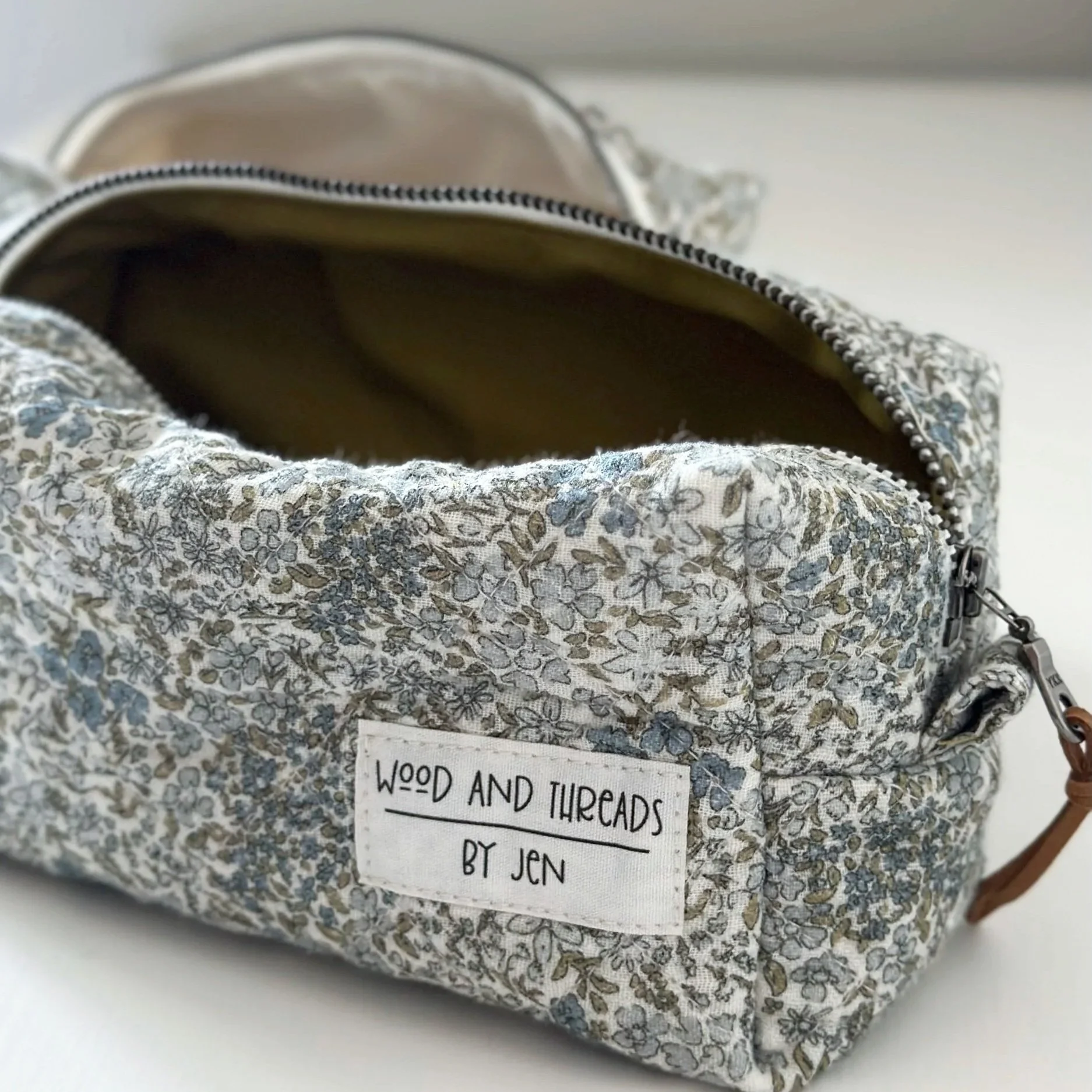 Green crosshatch boxy pouch unzipped to show olive cotton lining