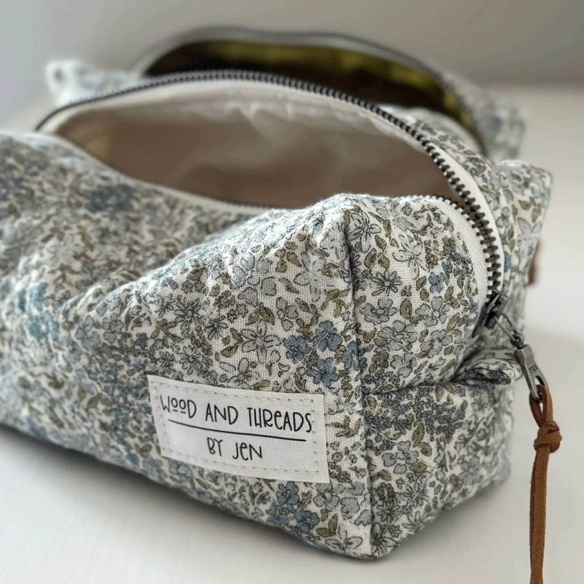 Open green crosshatch boxy pouch seen from above with olive lining