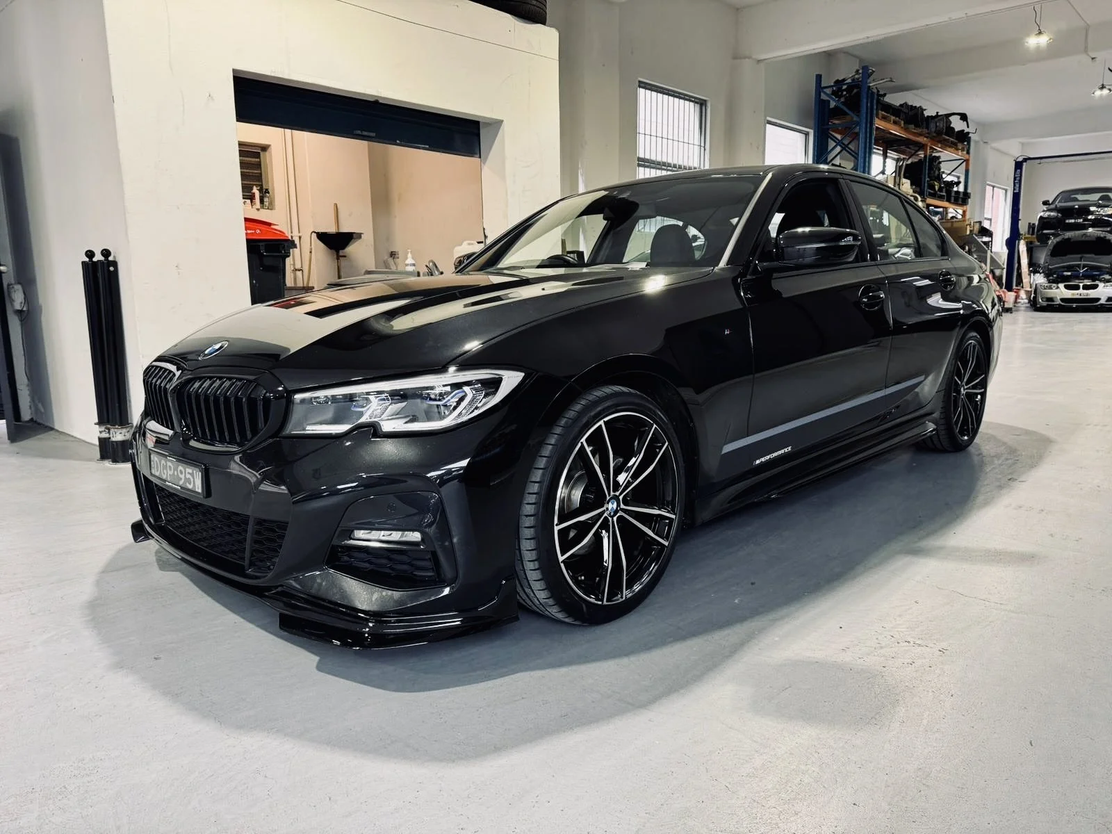 A black BMW sedan parked inside a garage or workshop.