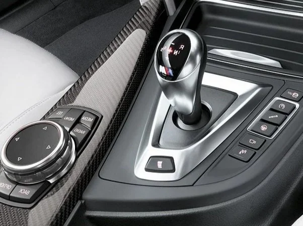 A close-up of a modern car's gear shift surrounded by control buttons and a textured dashboard.