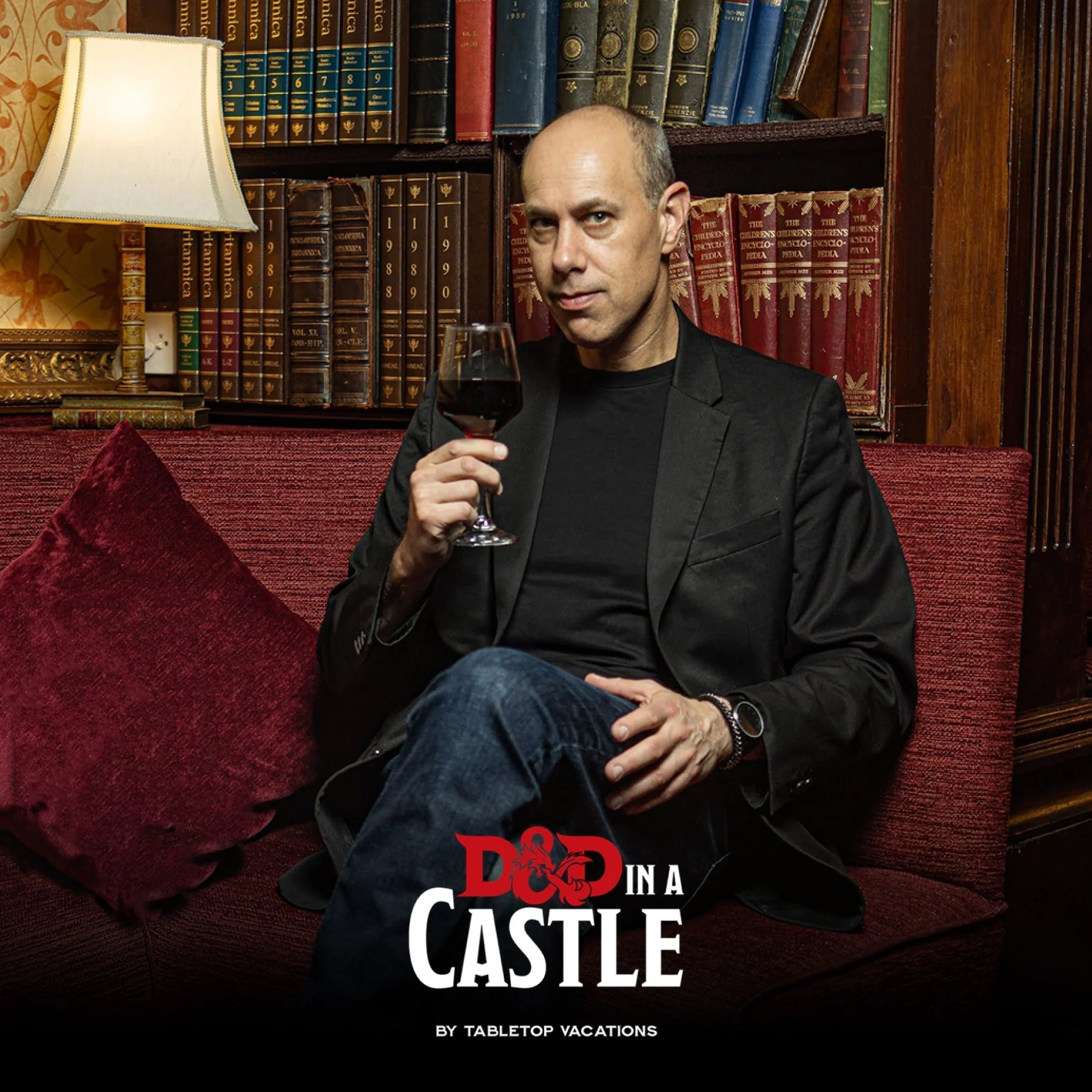 Male holding glass of red wine in front of bookshelf