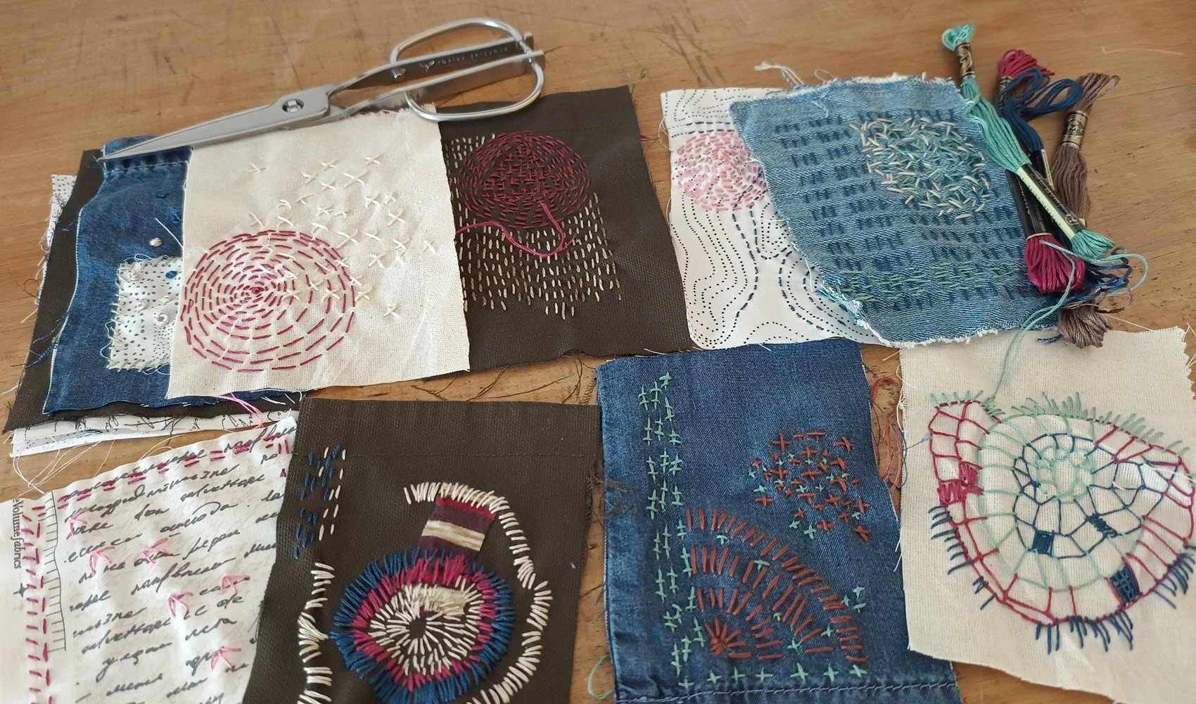 different post-card sized fabric squares with slow stitching patterns