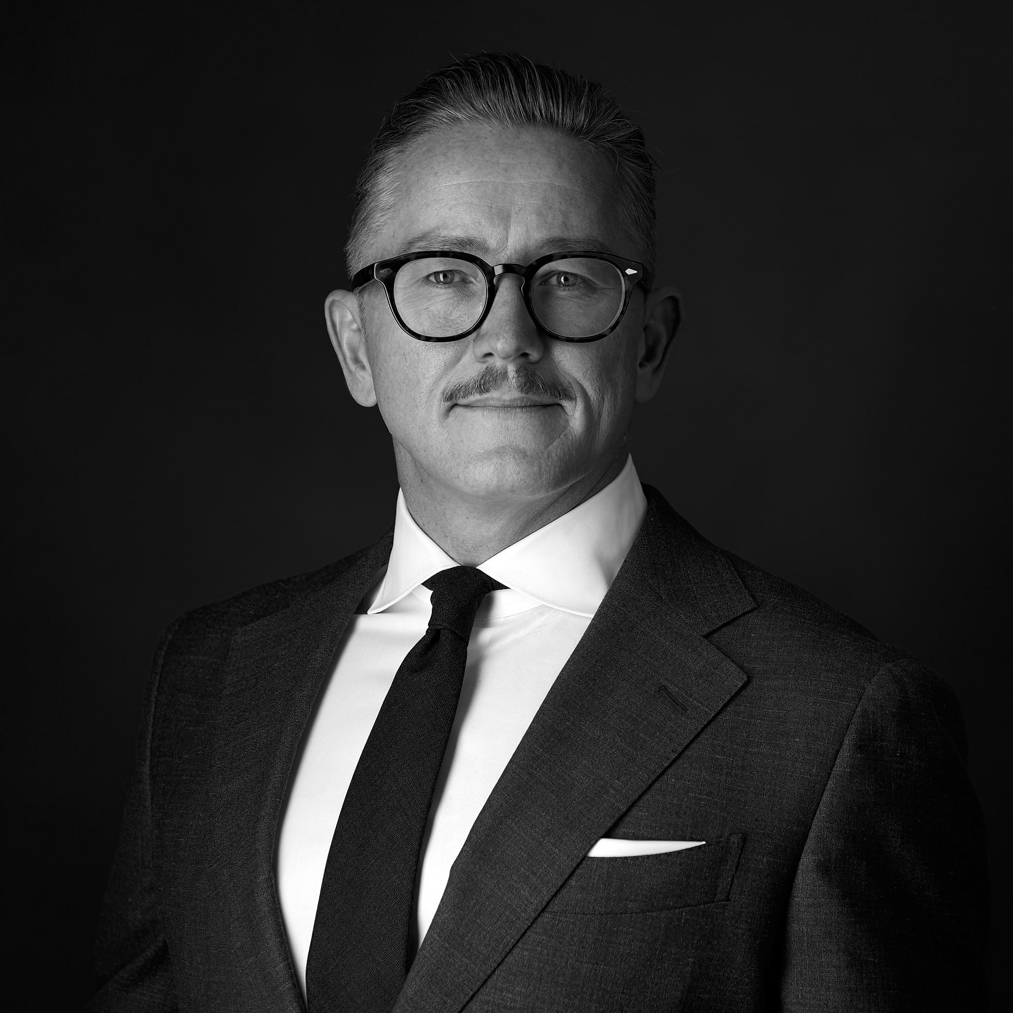 Corporate headshot in black and white of a man in a suit.