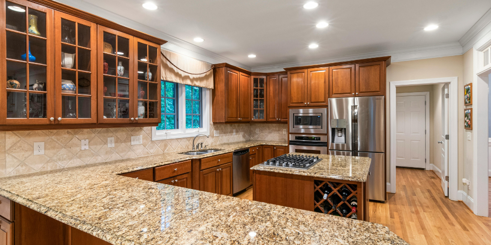 A traditional home kitchen with speckled granite stone countertops and an island