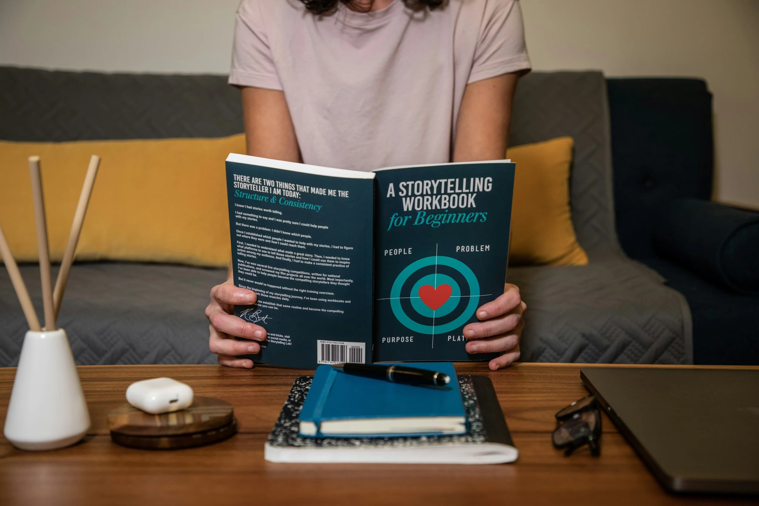 Person holding book entitled "A Storytelling Workbook for Beginners."