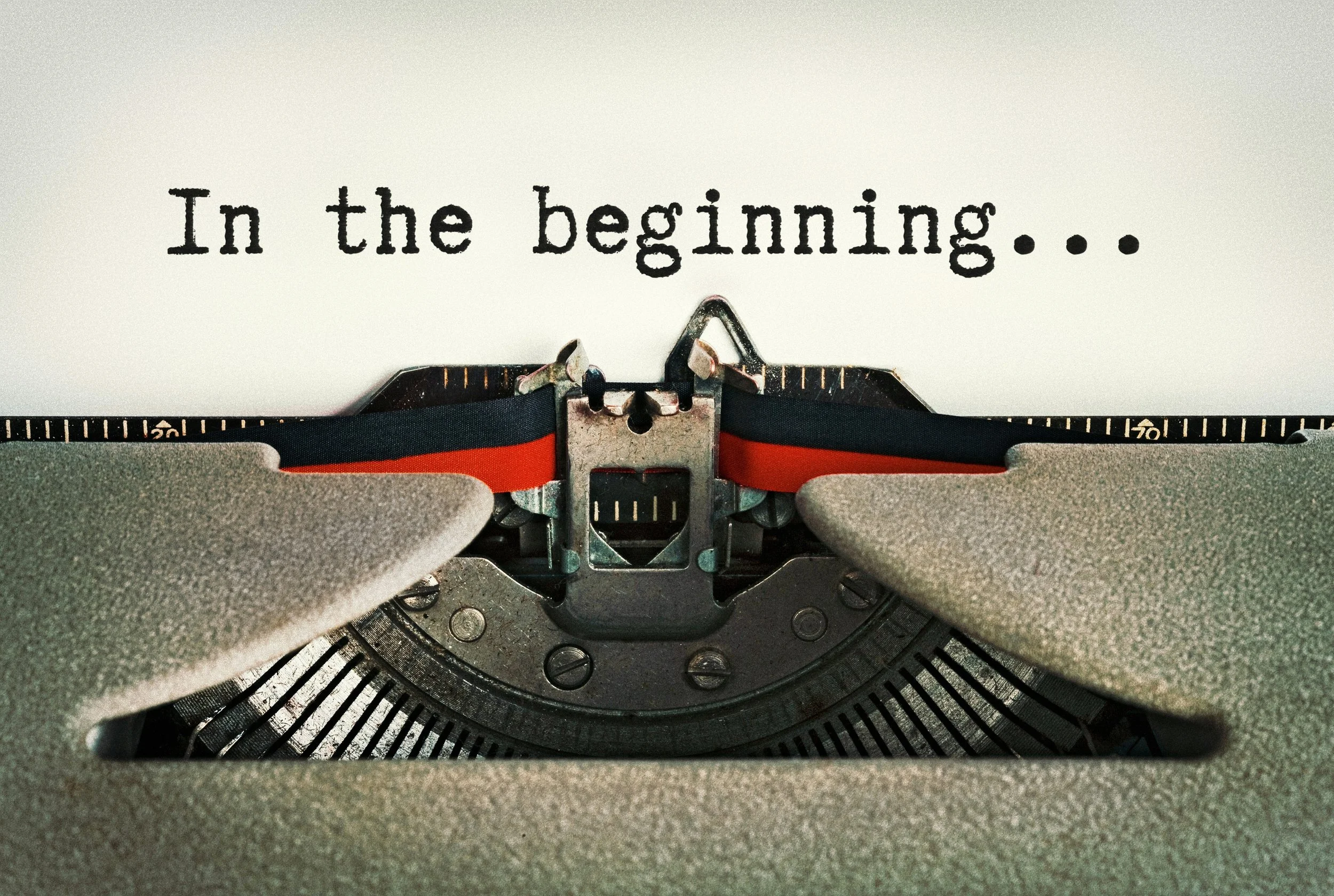 "In the beginning" appearing above the ribbon on a typewriter.
