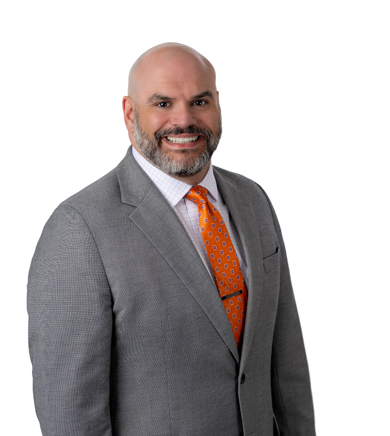 Portrait of a smiling bald man with a beard in a gray suit, checkered shirt, and orange patterned tie, against a white background.